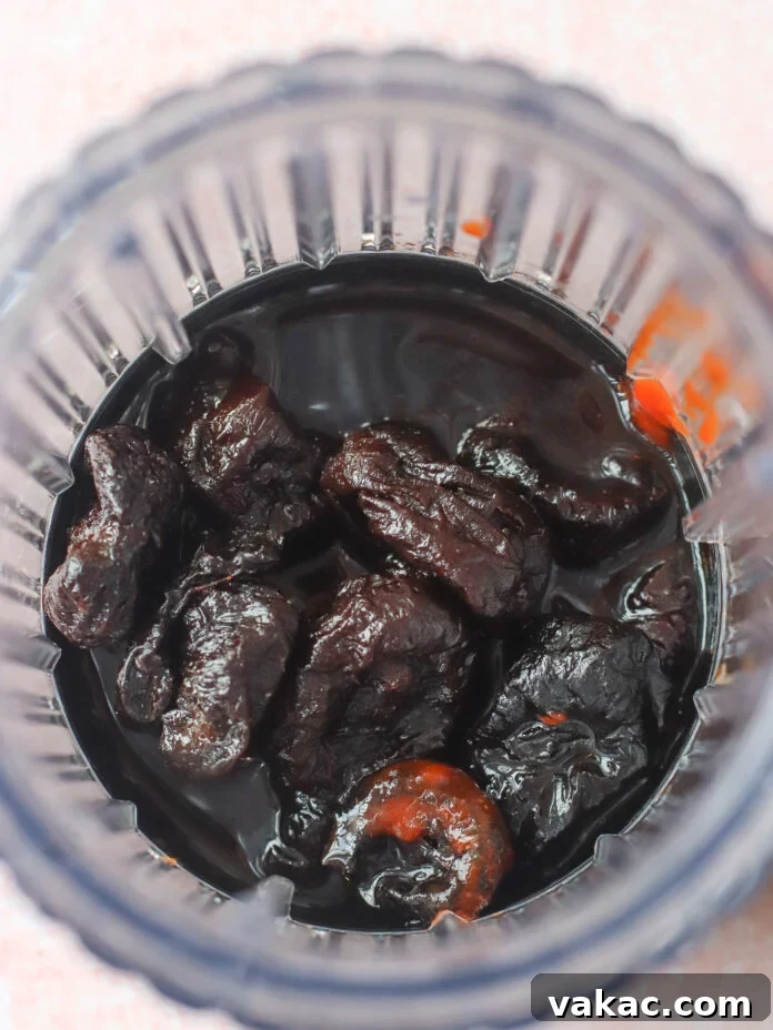 Quick Air Fryer Salmon Bowls: Sweet and Spicy Prune Delight 5 A close-up view of dark, dried prunes soaking in a thick, dark liquid inside a clear glass jar, seen from above, ready to be blended for the glaze.
