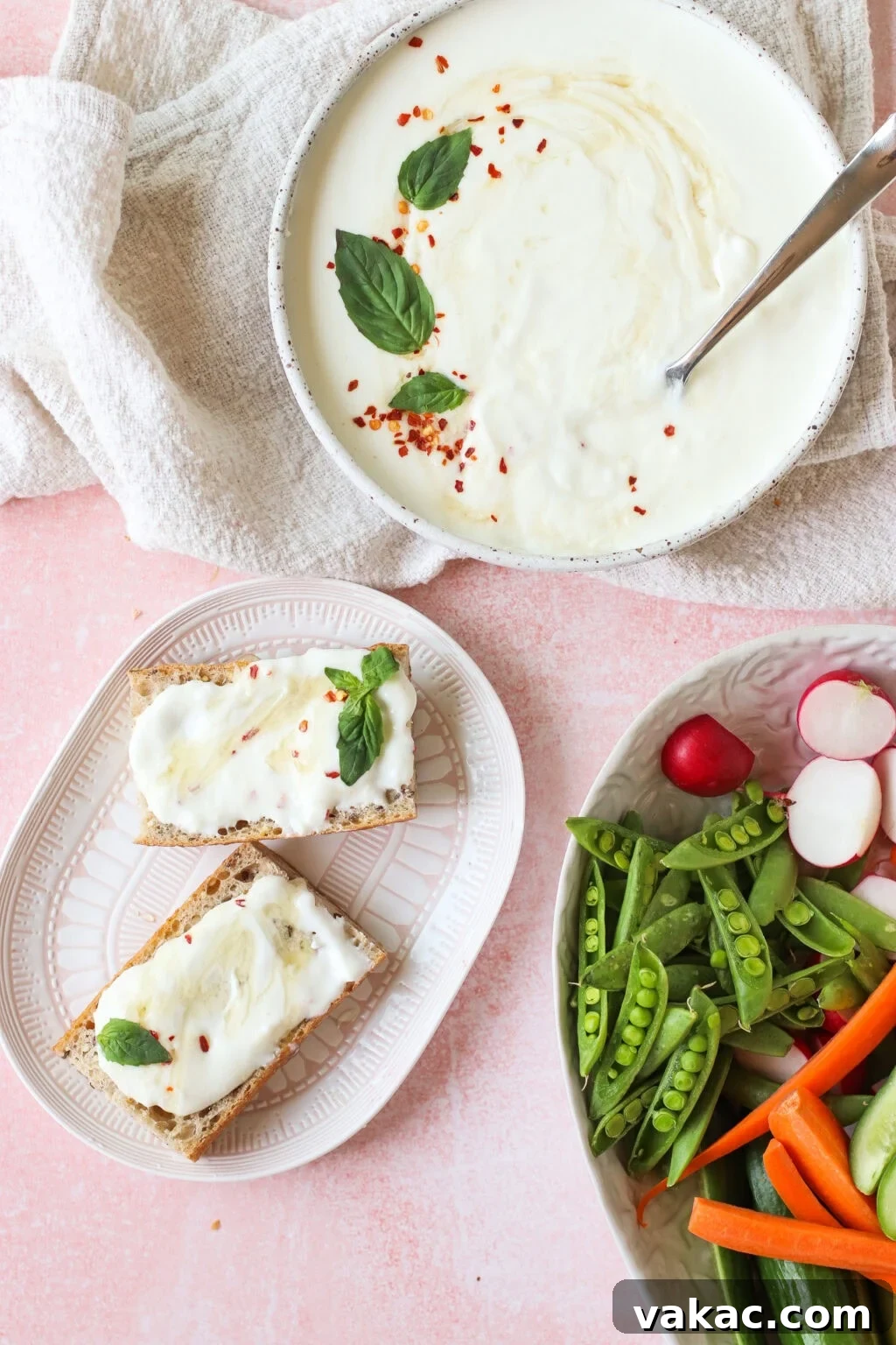 A beautifully arranged scene showcasing a bowl of creamy dip, elegantly garnished with fresh basil and a sprinkle of chili flakes. Alongside, a plate holds two slices of toasted bread, each generously spread with the delectable dip. Completing the ensemble is a colorful platter of fresh vegetables, featuring crisp snap peas, vibrant carrot sticks, and thinly sliced radishes, creating a perfect balance of flavors and textures.