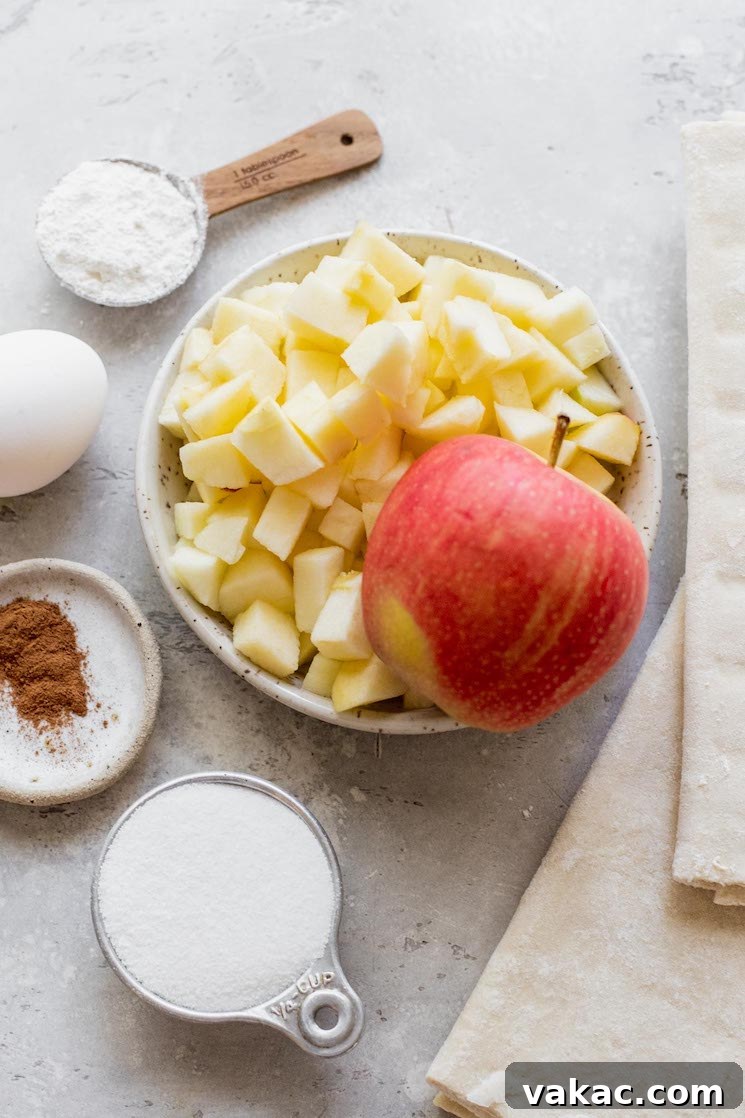 A rustic gray surface displaying all the essential ingredients for making apple turnovers.