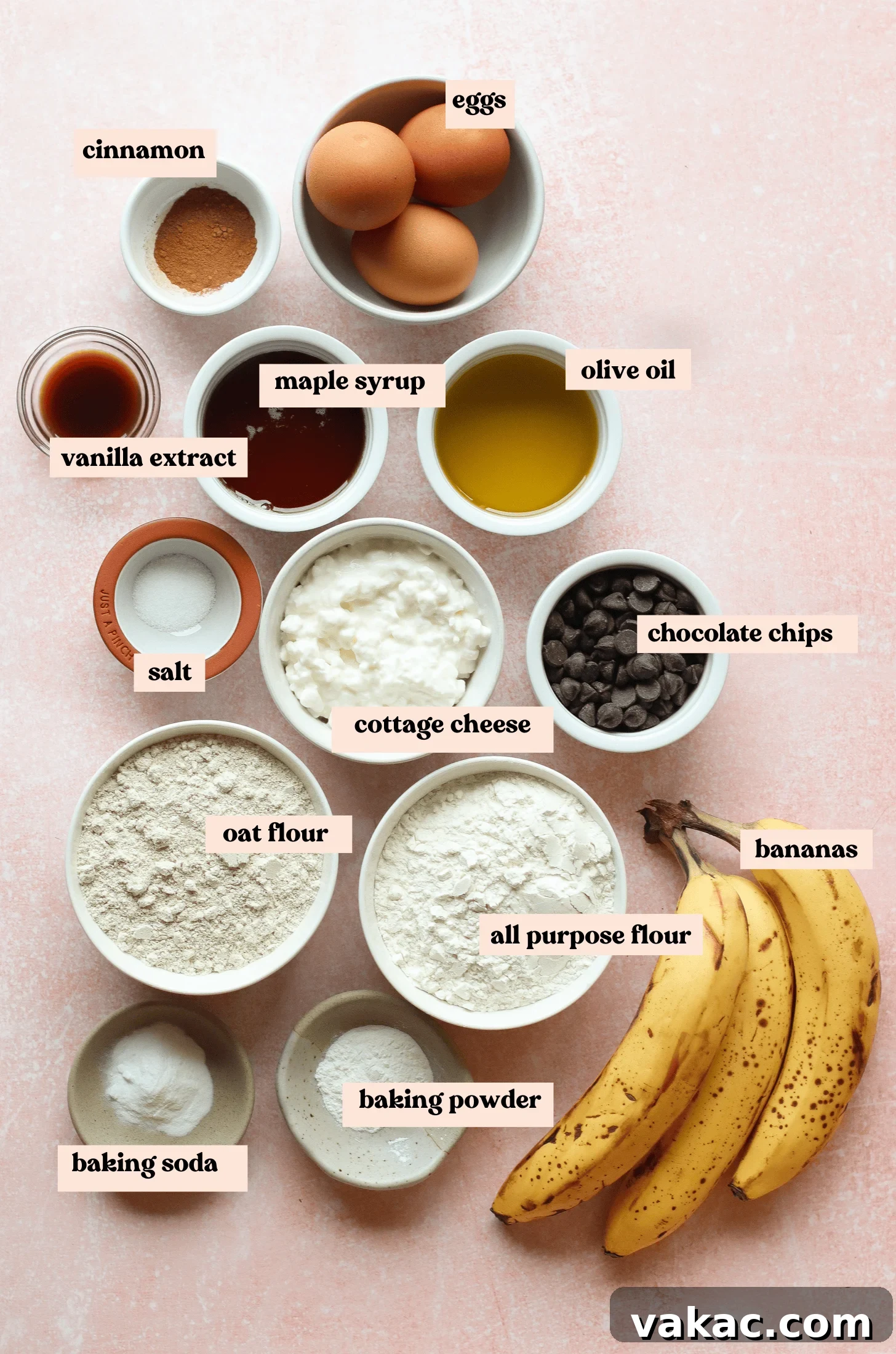 Super Moist Cottage Cheese Banana Bread Protein Boost 3 A vibrant flat lay of essential baking ingredients arranged on a stylish pink surface, featuring fresh eggs, cinnamon sticks, pure vanilla extract, golden maple syrup, healthy olive oil, fine sea salt, delectable chocolate chips, nutritious oat flour, perfectly ripe bananas, and creamy cottage cheese – all ready for crafting the perfect cottage cheese banana bread.