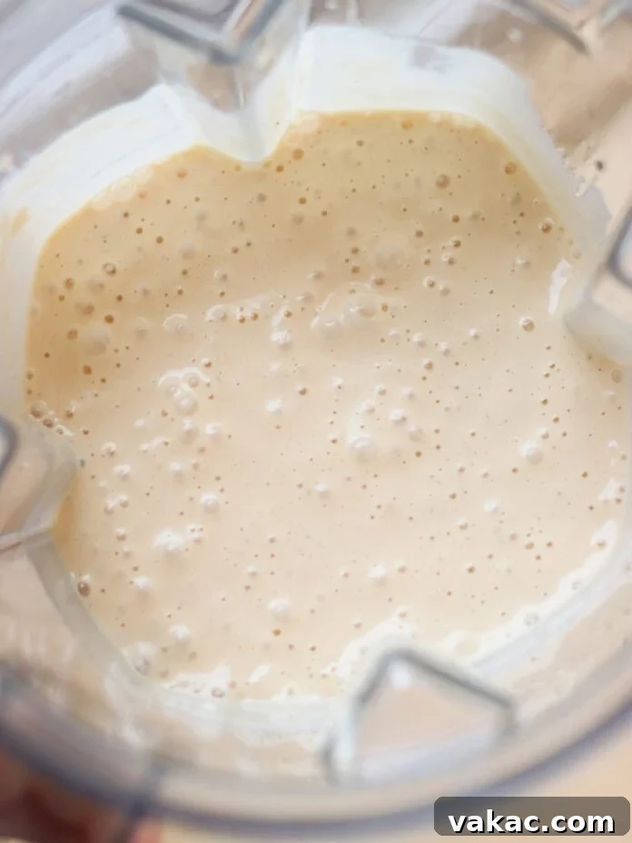 Super Moist Cottage Cheese Banana Bread Protein Boost 5 A creamy, lightly frothy batter or smoothie mixture swirling smoothly within a clear blender, with small bubbles indicating its silky texture.