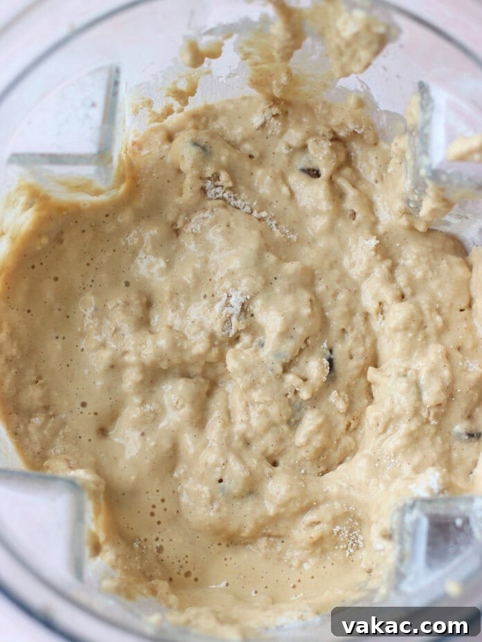 Super Moist Cottage Cheese Banana Bread Protein Boost 6 A close-up view of thick, lumpy batter with visible chunks, inside a clear blender container. The mixture appears creamy and lightly golden in color.