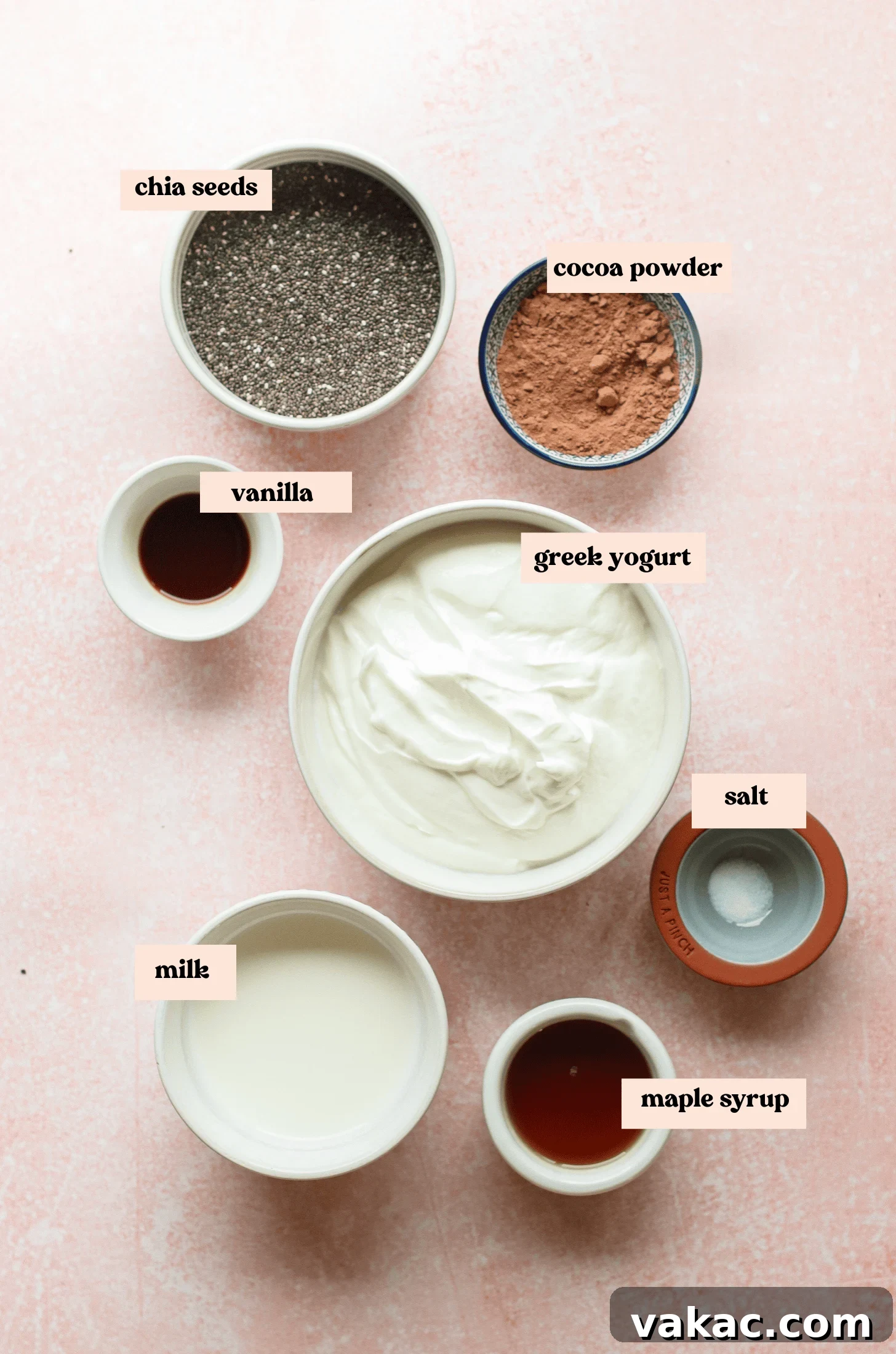 Velvet Chocolate Chia Protein Pudding with Greek Yogurt 3 Bowls of ingredients labeled chia seeds, cocoa powder, vanilla, Greek yogurt, salt, milk, and maple syrup are arranged on a light pink surface.