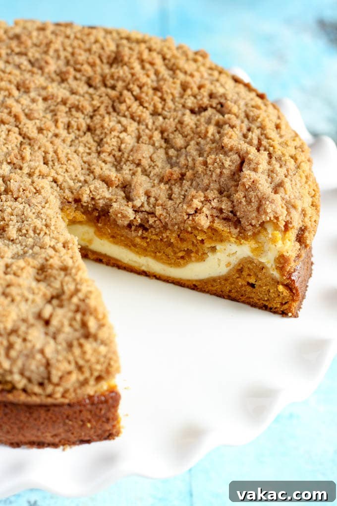 Close-up of a slice of Pumpkin Cream Cheese Crumb Cake showing the layers of cake, cream cheese, and crumb