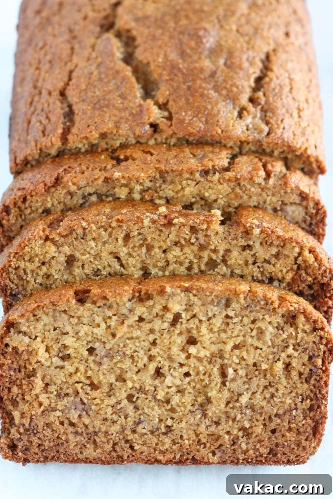 Nourishing Whole Grain Banana Loaf 2 A loaf of whole wheat banana bread. The front section has been cut into three slices.