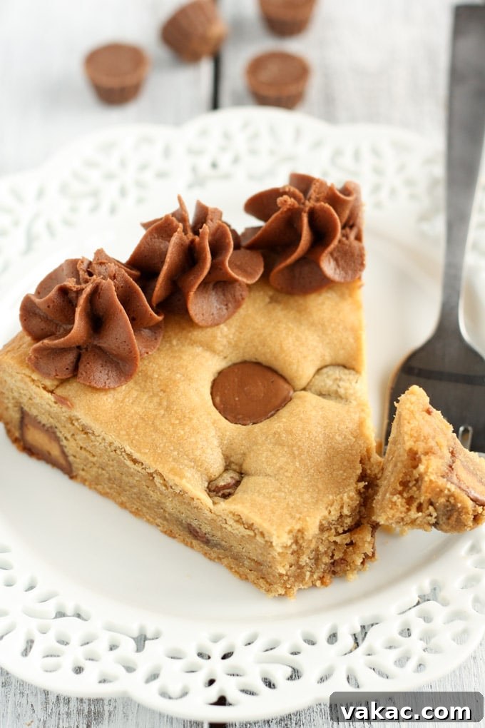Ultimate Peanut Butter Cup Cookie Cake 4 A beautifully frosted peanut butter cup cookie cake, with a small slice missing, presented as the main recipe image.