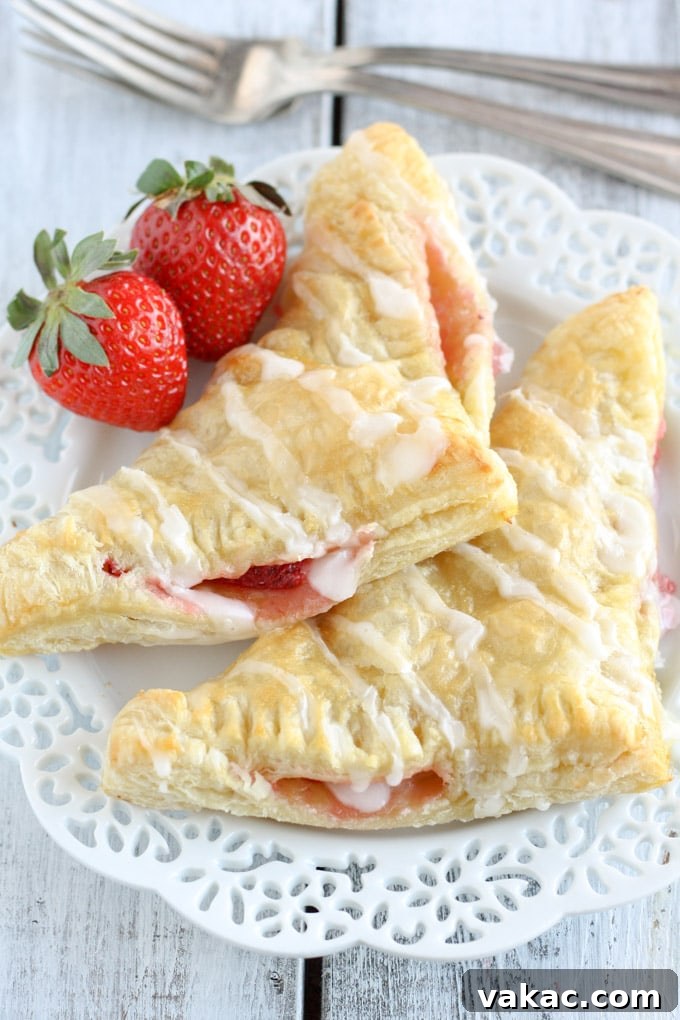 Flaky Strawberry Cream Cheese Pockets 5 A perfectly baked strawberry turnover, golden brown and flaky, with a hint of its sweet strawberry and creamy cheese filling peeking out. This image serves as the main visual for the recipe.
