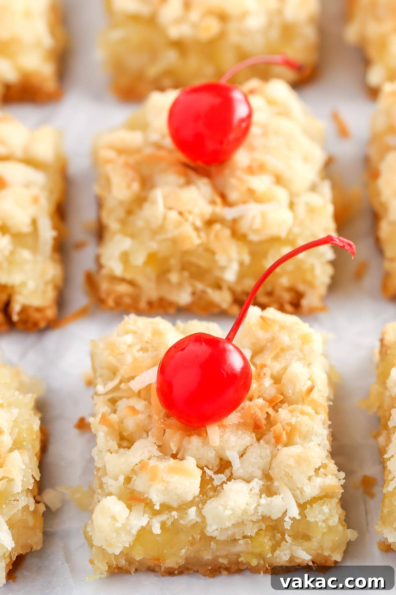 Golden Pineapple Squares 3 Three rows of sliced pineapple coconut bars. The front two have been garnished with maraschino cherries.
