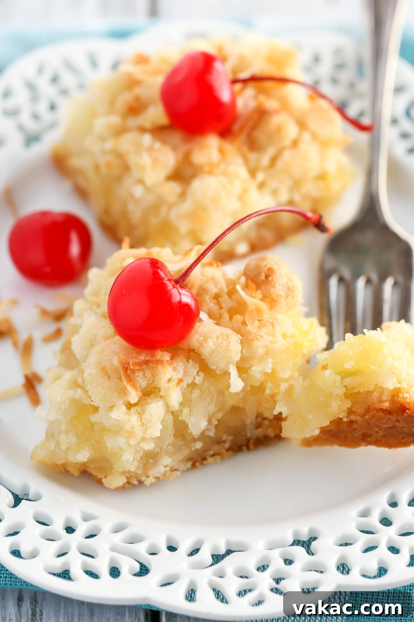 Golden Pineapple Squares 4 Two pineapple bars on a white dessert plate with a fork. A piece of the front bar is speared on the fork.