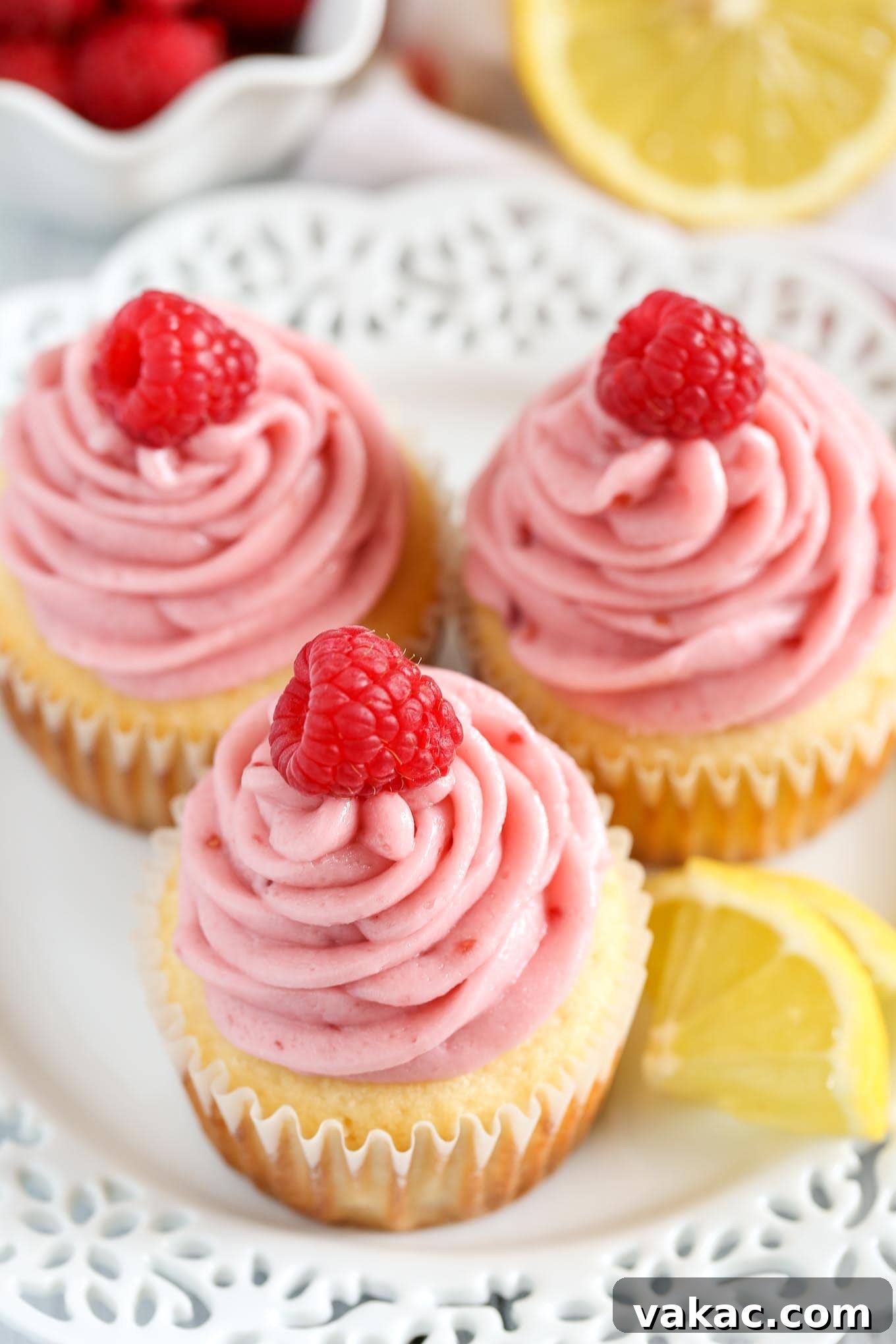 Lemon Raspberry Bliss Cupcakes 5 Top-down view of beautifully frosted lemon cupcakes with raspberry buttercream and fresh raspberries arranged on a pristine white plate.