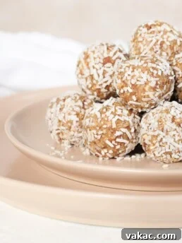 A pyramid of coconut lemon energy balls sit on a pink plate. The image is zoomed in so you only see half of the pyramid. The balls are covered in shredded coconut