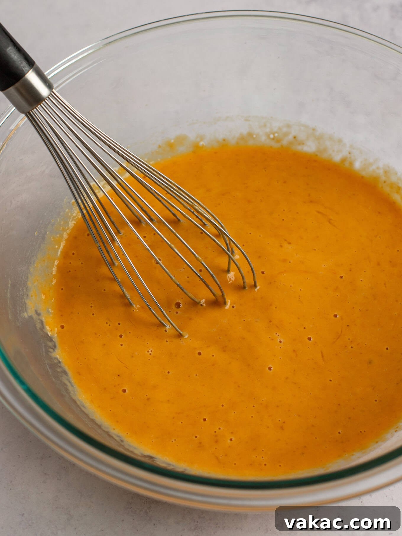 Autumn's Golden Slice 12 The wet ingredients for pumpkin pie filling—beaten eggs, pumpkin puree, and evaporated milk—whisked smooth in a clear glass mixing bowl.