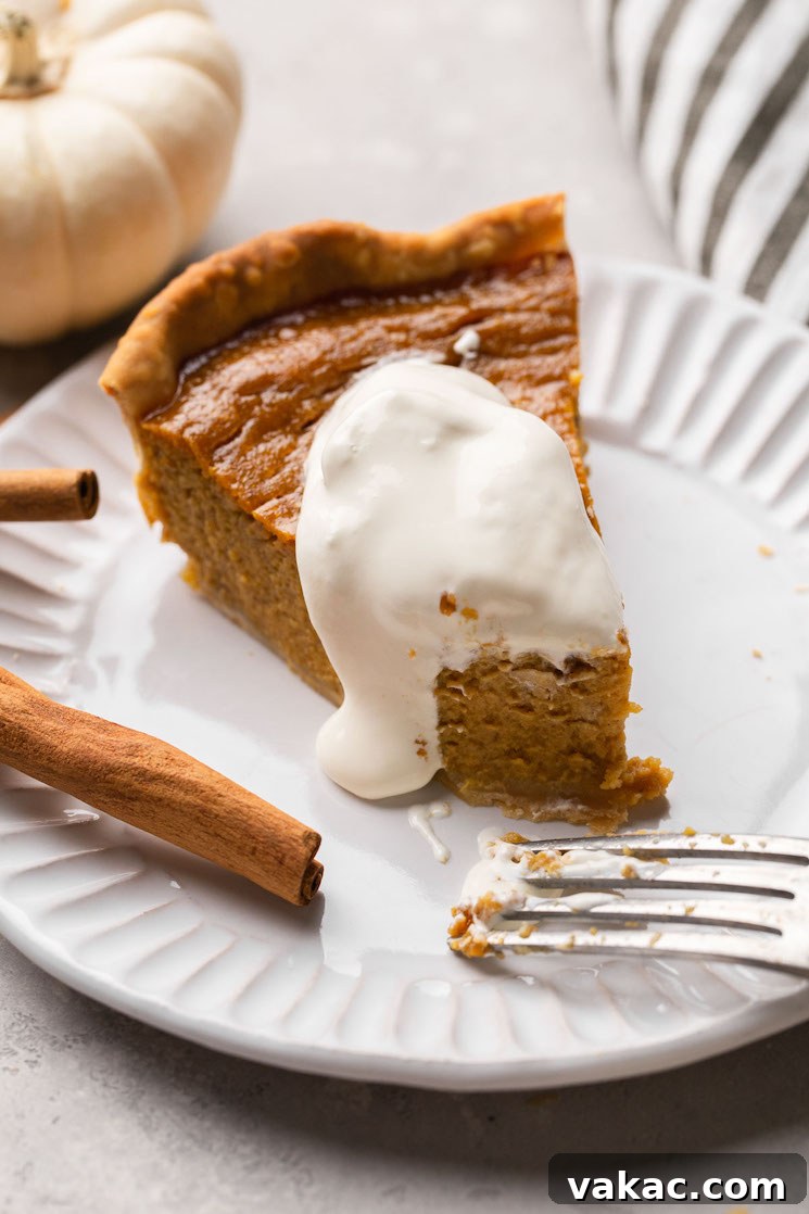 Autumn's Golden Slice 16 A perfectly portioned slice of homemade pumpkin pie, generously topped with fluffy whipped cream, resting on a pristine white plate.