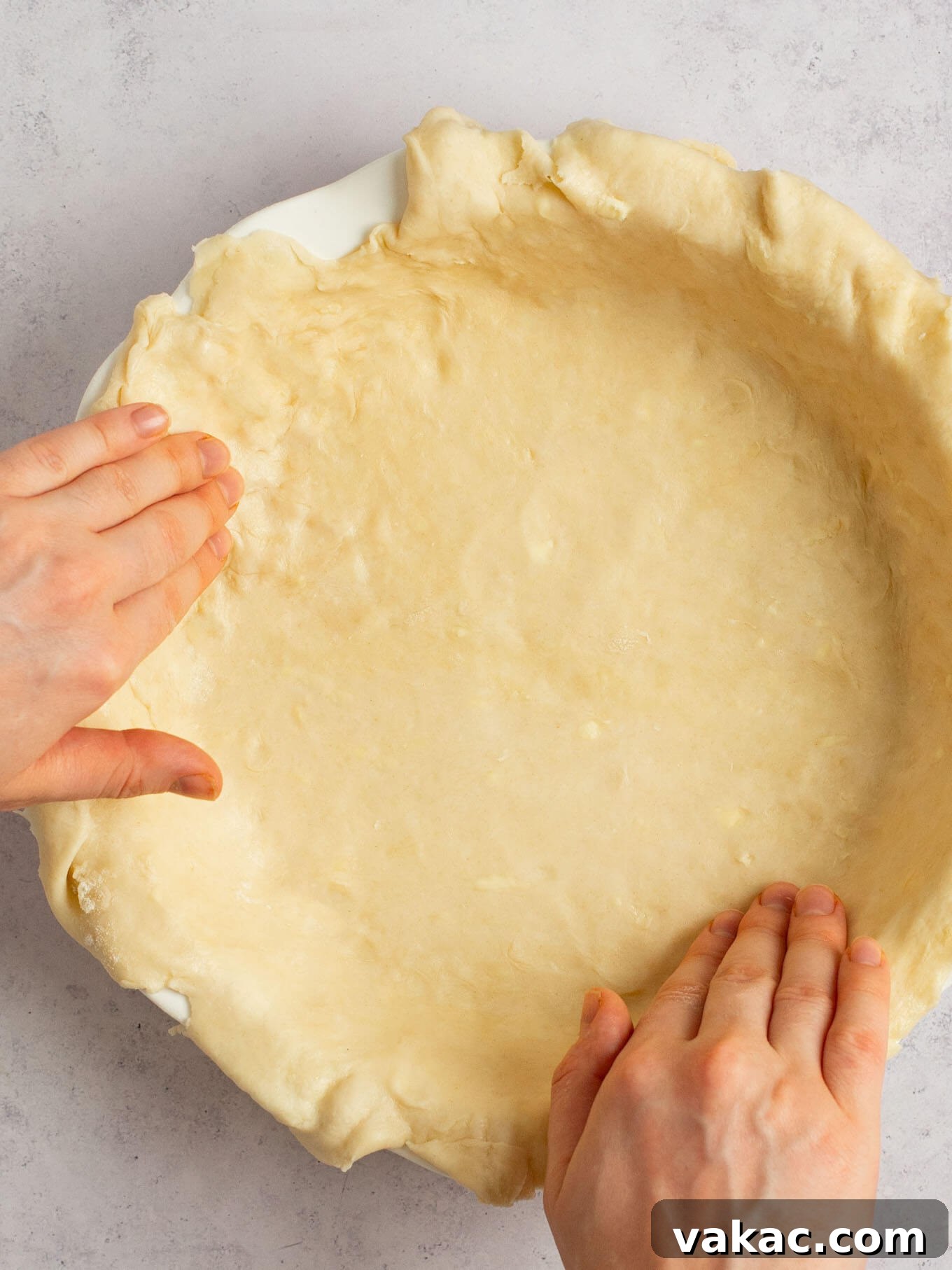 Autumn's Golden Slice 5 Hands carefully fitting rolled-out pie dough into a white ceramic pie dish, ensuring it's evenly placed.