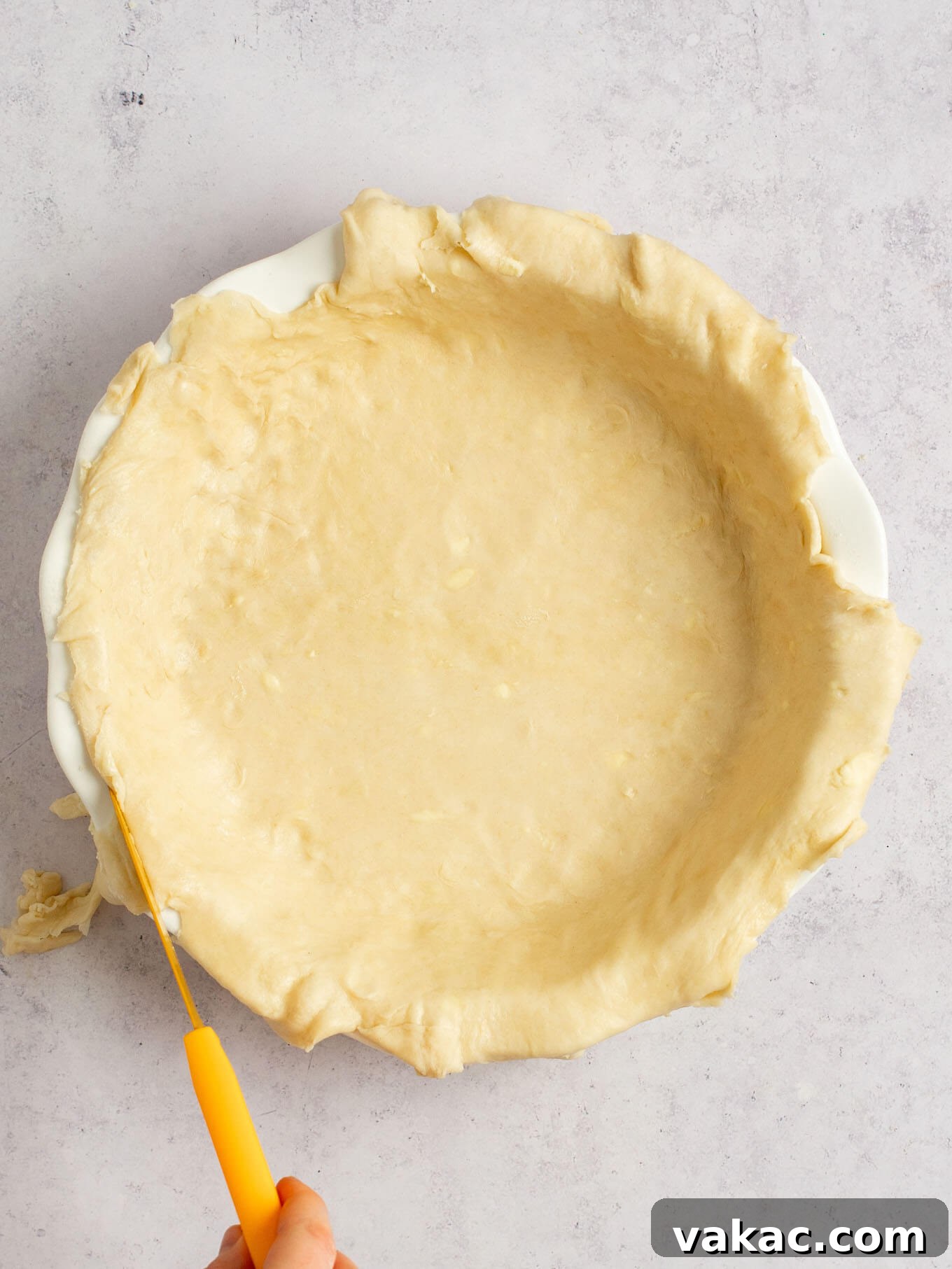 Autumn's Golden Slice 6 An overhead view of pie dough in a pie dish, with a knife being used to trim the excess edges for a neat finish.