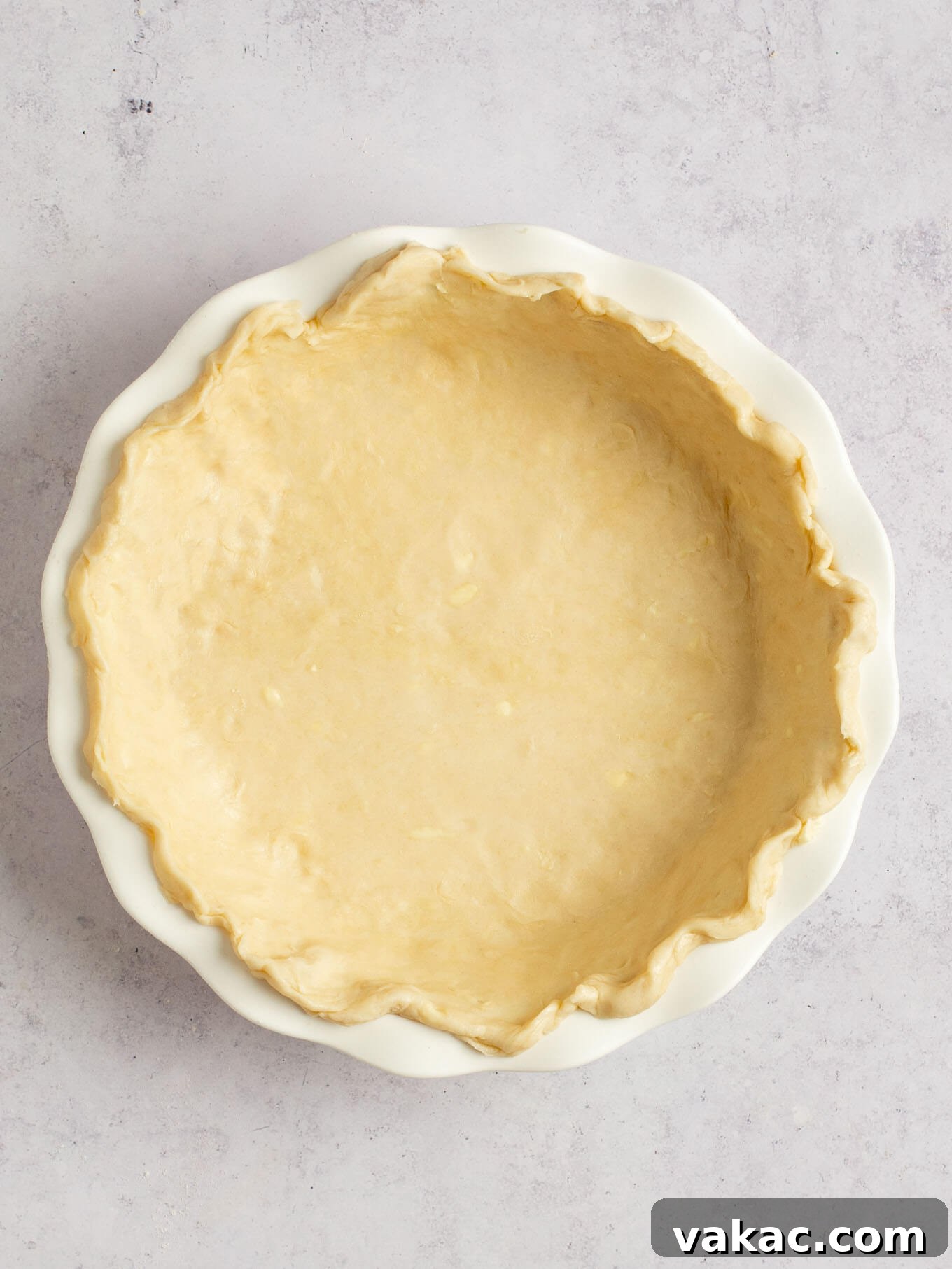 Autumn's Golden Slice 7 Pie dough beautifully fitted into a white pie dish, with the edges carefully crimped and decorated.