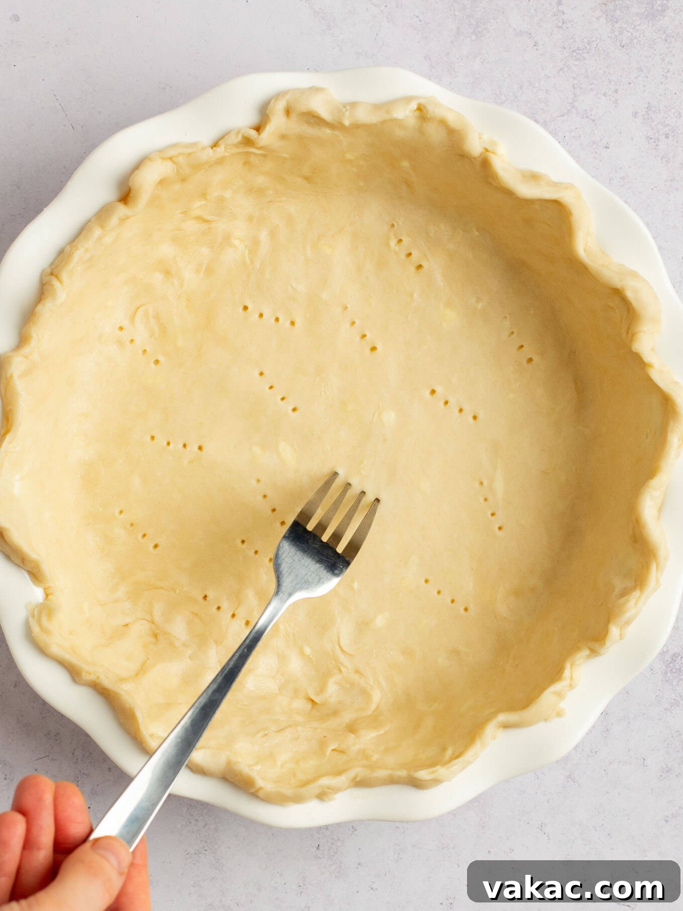 Autumn's Golden Slice 8 An overhead view of a fork being used to methodically poke holes across the bottom of the raw pie crust.