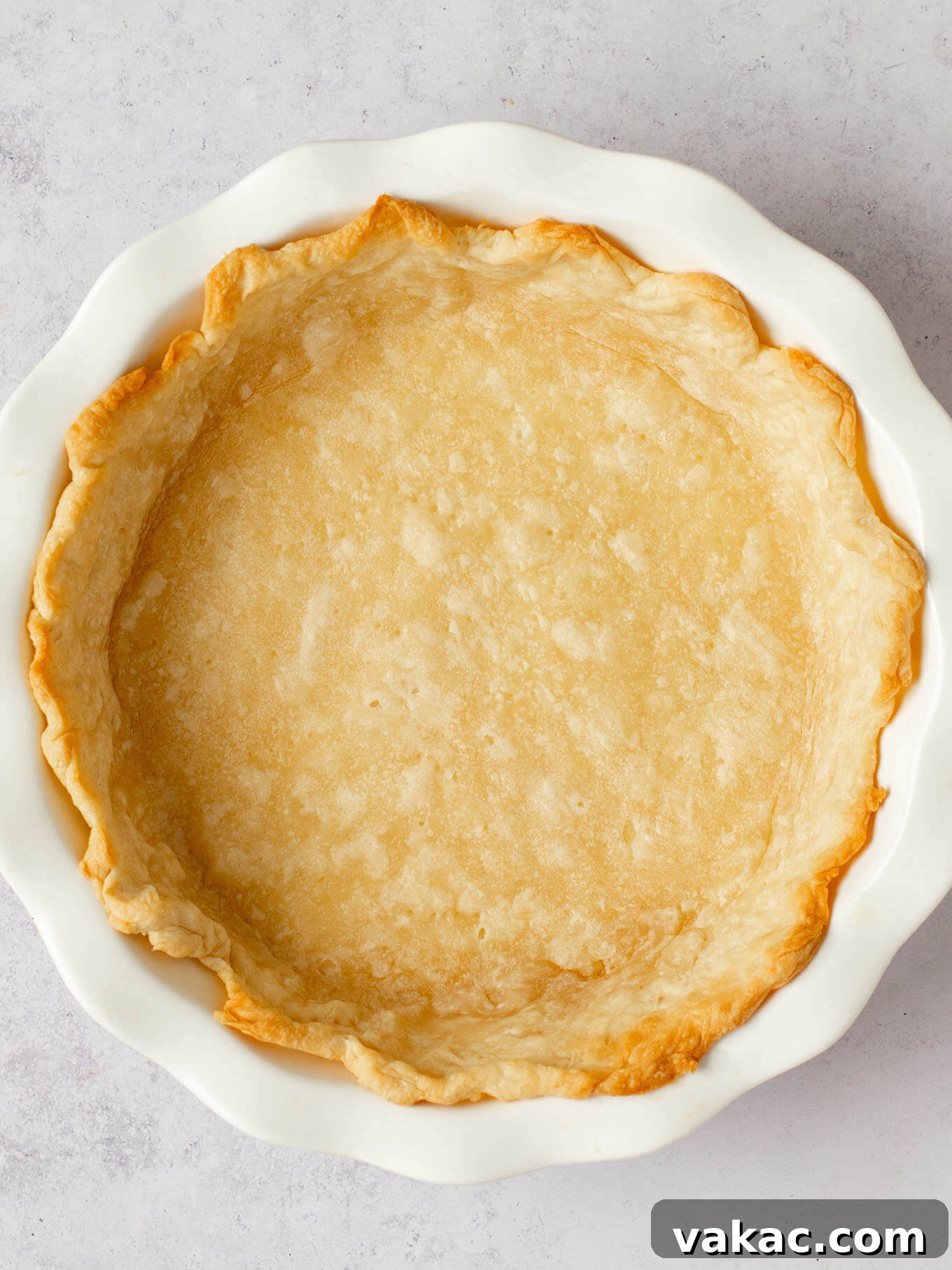 Autumn's Golden Slice 10 A partially baked, golden-brown pie crust resting in a white ceramic pie dish after blind baking.