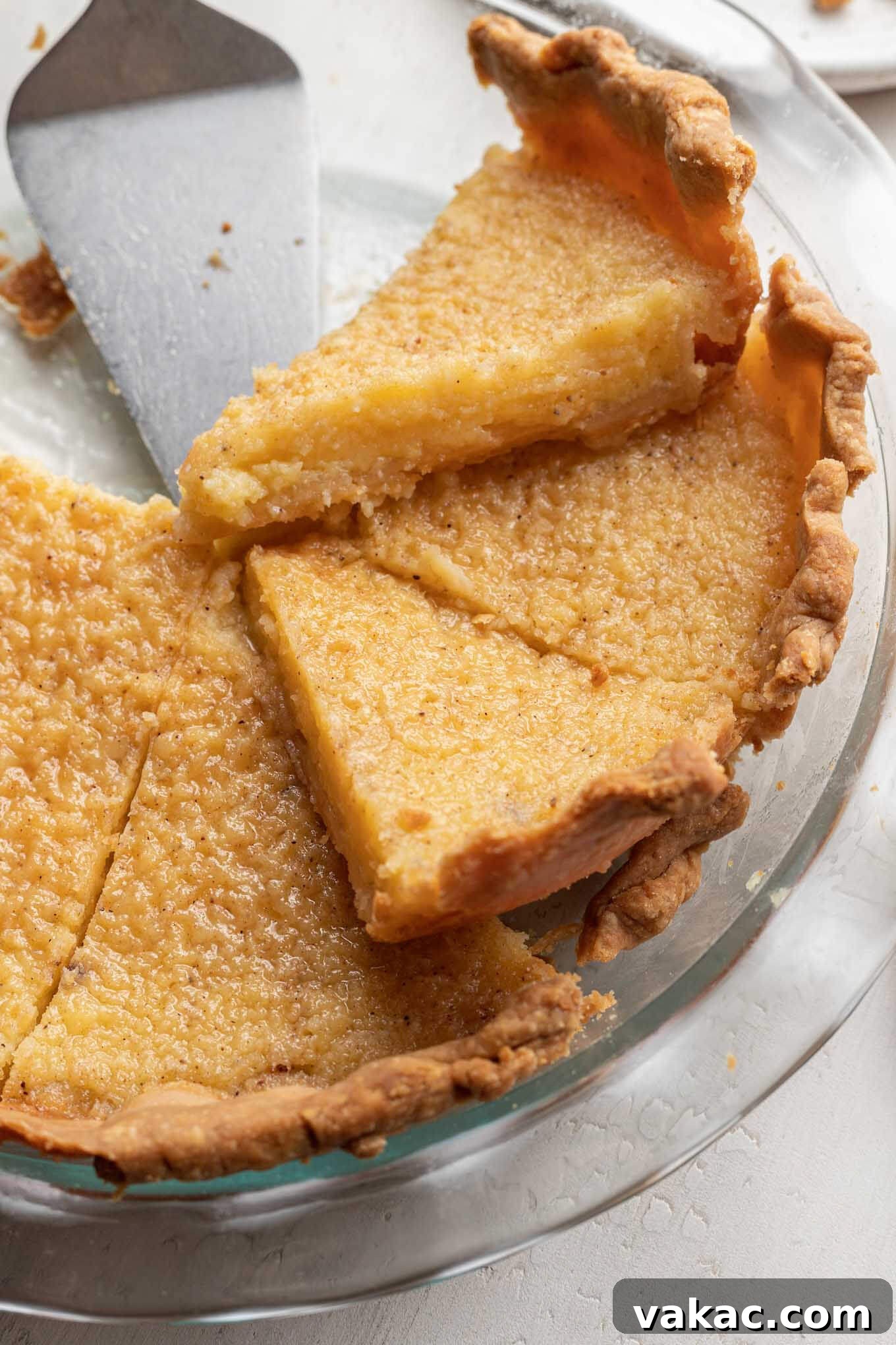 Southern Sunshine Pie 6 A beautifully sliced Southern buttermilk pie, revealing its smooth, golden custard filling and flaky crust, still in the glass pie plate.
