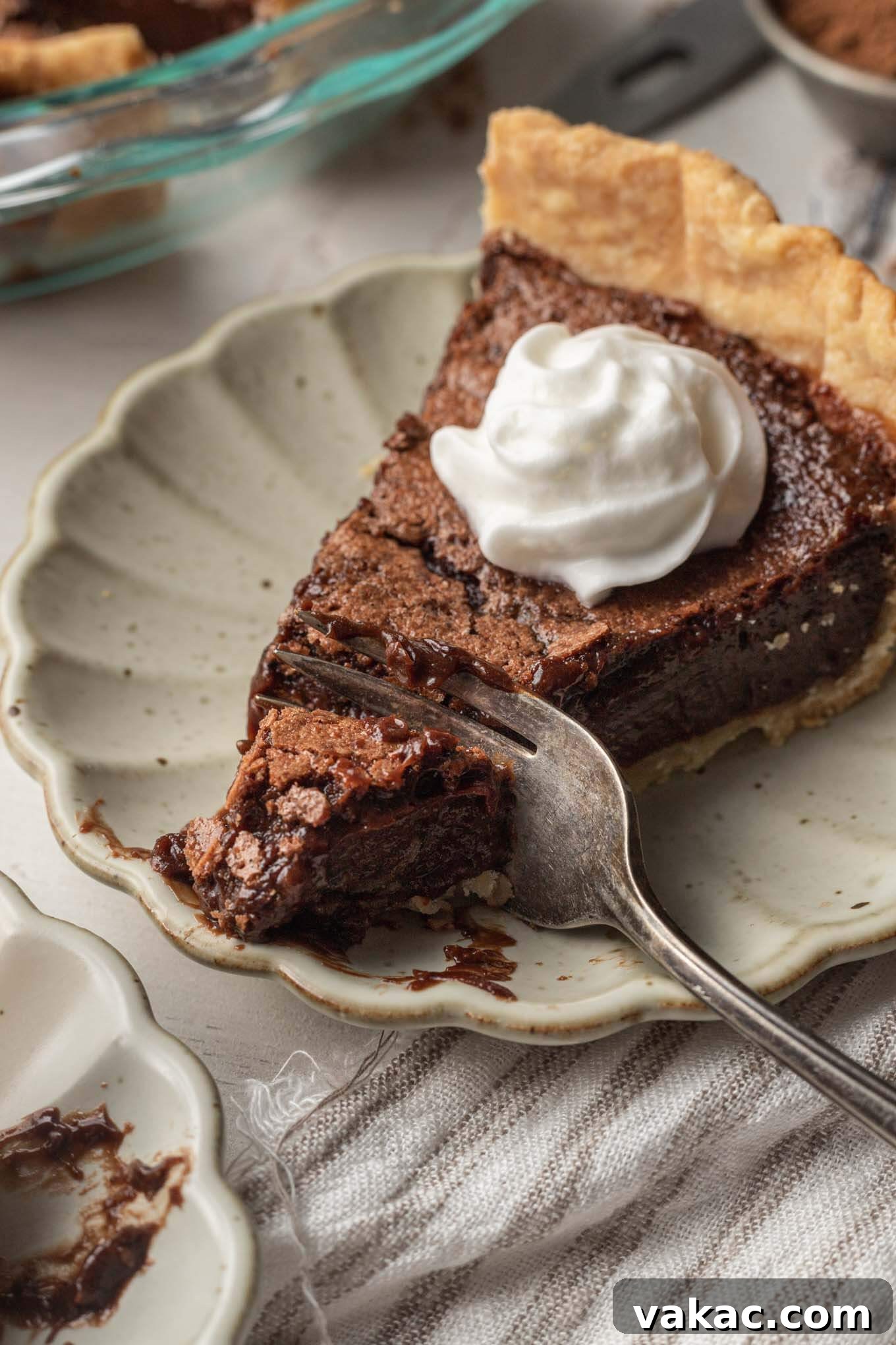 Decadent Chocolate Dream Pie 9 A slice of chocolate chess pie topped with whipped cream. A fork is digging into the pie.