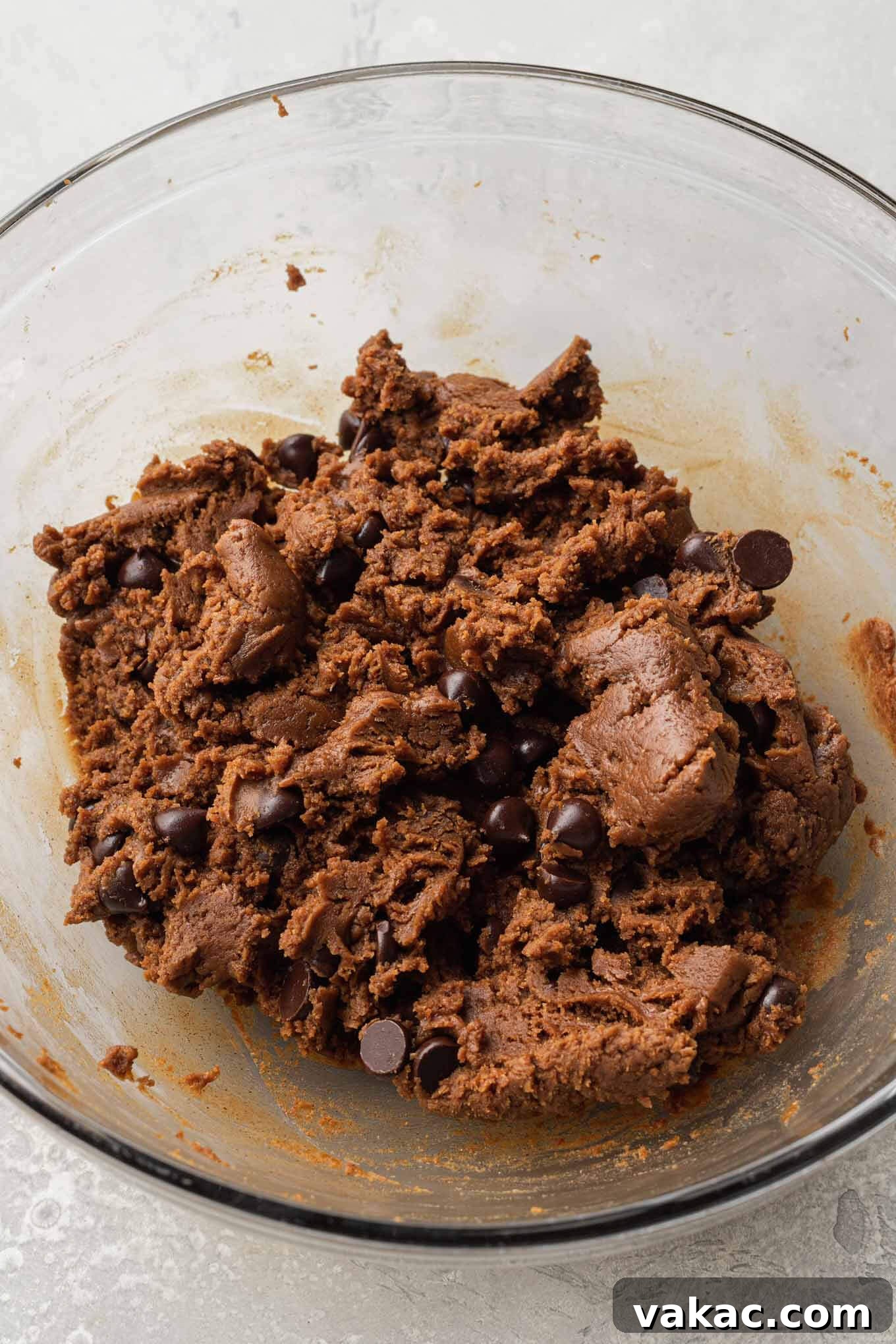 An overhead view of almond butter cookie dough mixed with delectable chocolate chips, glistening in a mixing bowl, ready for scooping.