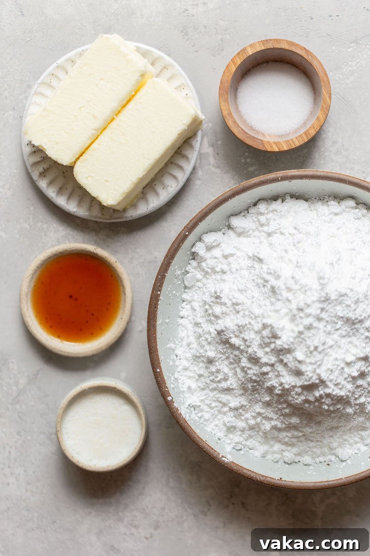All the essential ingredients for making a batch of smooth buttercream frosting, including butter, powdered sugar, heavy cream, vanilla extract, and a pinch of salt, neatly arranged in small bowls on a gray kitchen counter.