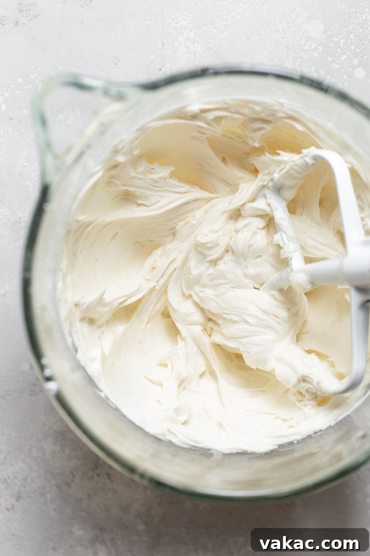 A glass mixing bowl proudly displays a perfectly finished batch of luscious homemade buttercream frosting, ready to be used for decorating cakes or cupcakes.