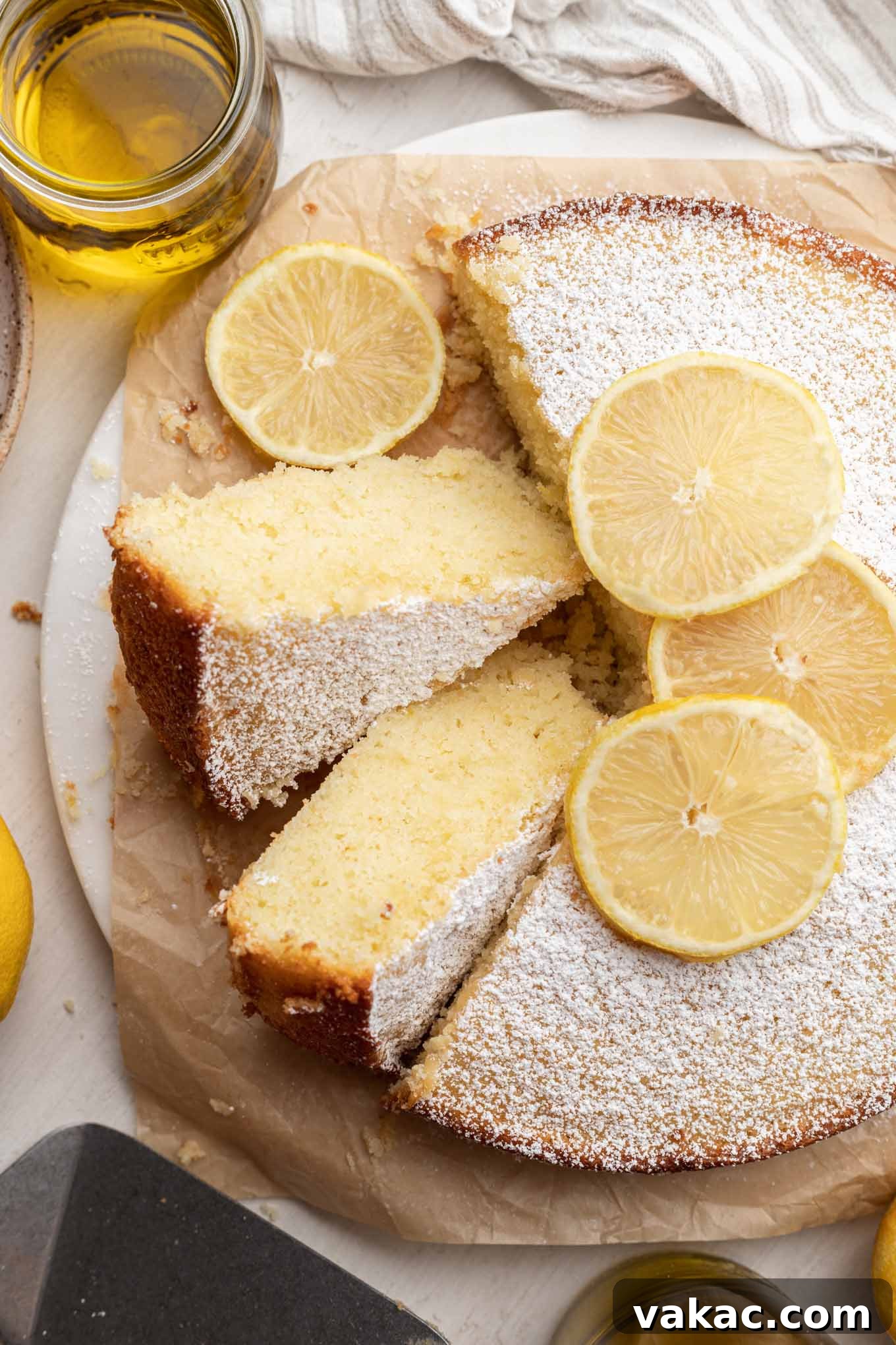Sunshine Citrus Olive Oil Cake 2 An overhead view of a beautifully baked lemon olive oil cake, with two slices turned on their sides, showcasing its soft, moist texture and golden crust.