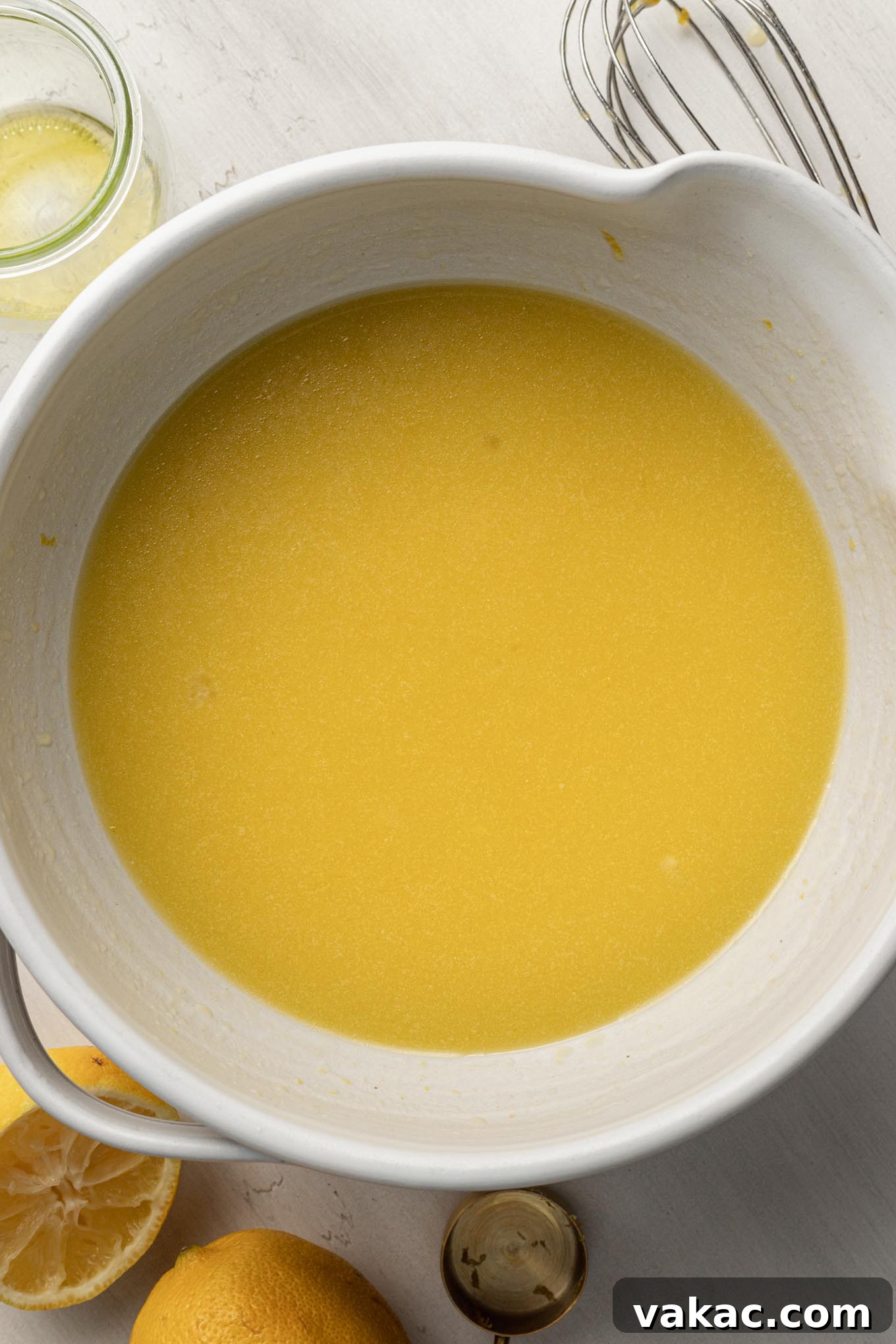 Sunshine Citrus Olive Oil Cake 4 An overhead view of the wet ingredients, including olive oil, buttermilk, and eggs, being whisked together in a pristine white mixing bowl.