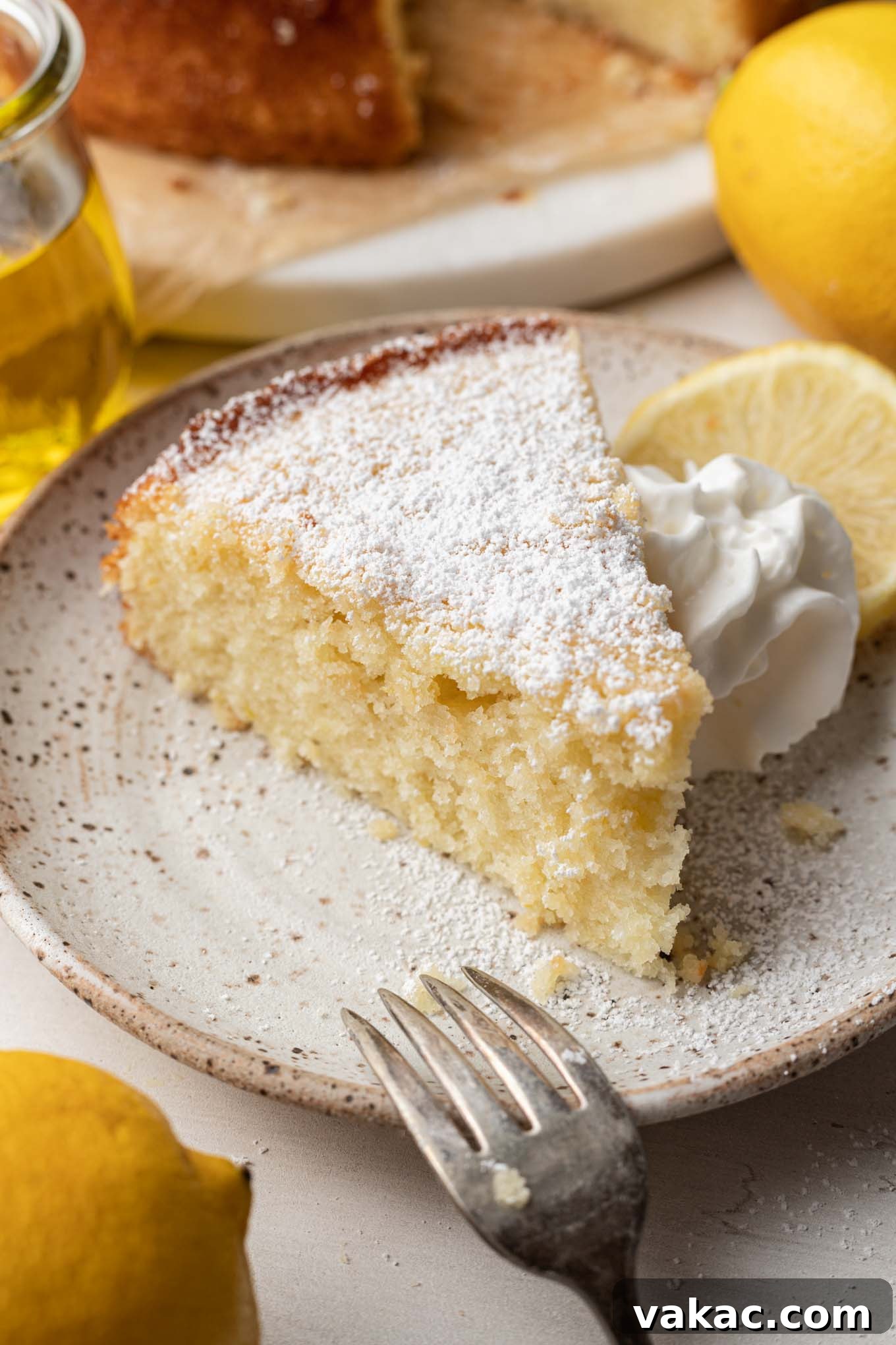 Sunshine Citrus Olive Oil Cake 7 A single, delectable slice of olive oil cake artfully placed on a white dessert plate, with its golden crust and delicate crumb visible.