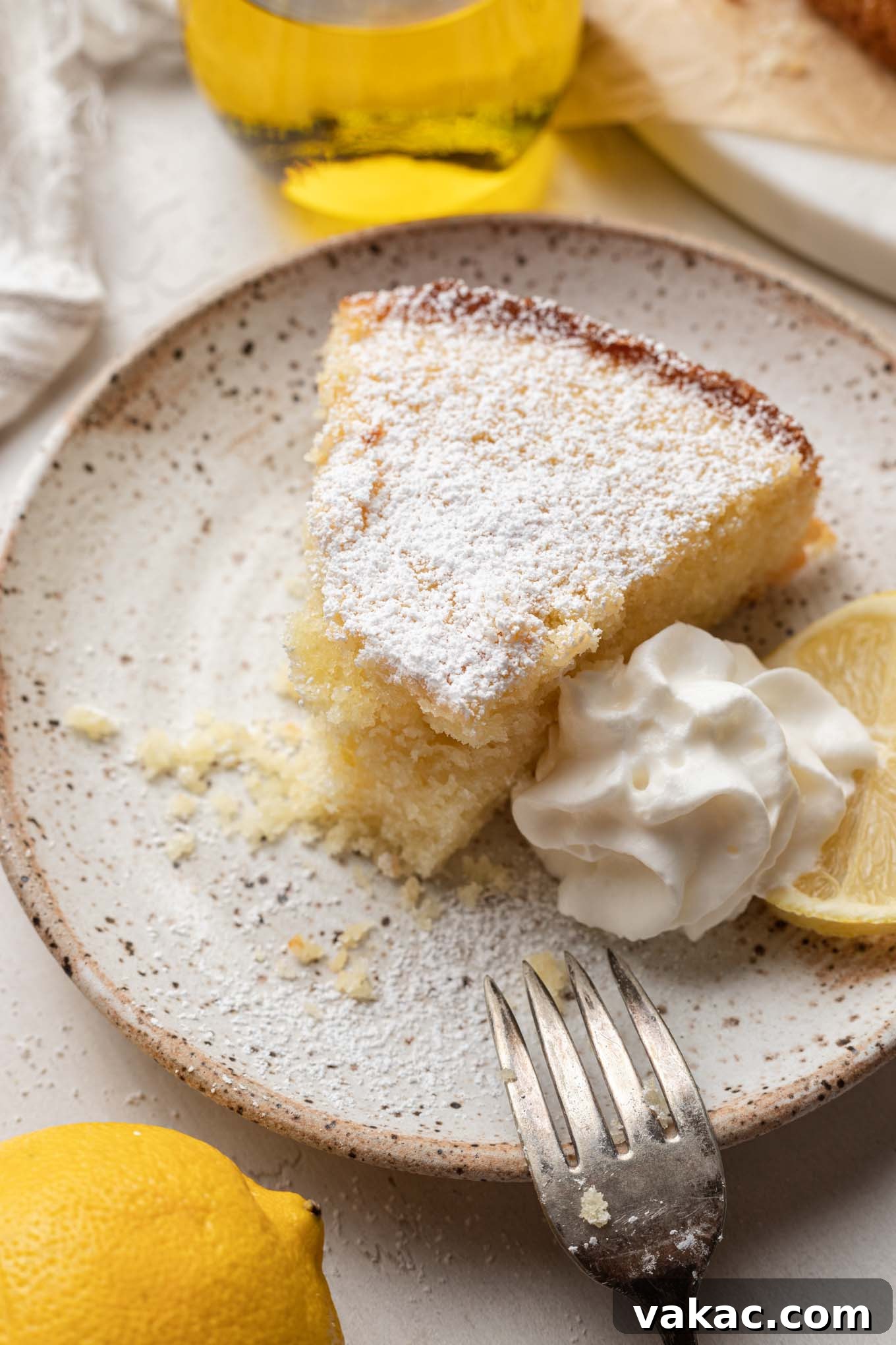 Sunshine Citrus Olive Oil Cake 8 A close-up view of a slice of olive oil lemon cake with a bite missing, perfectly showcasing its fluffy, moist interior and delicate texture.