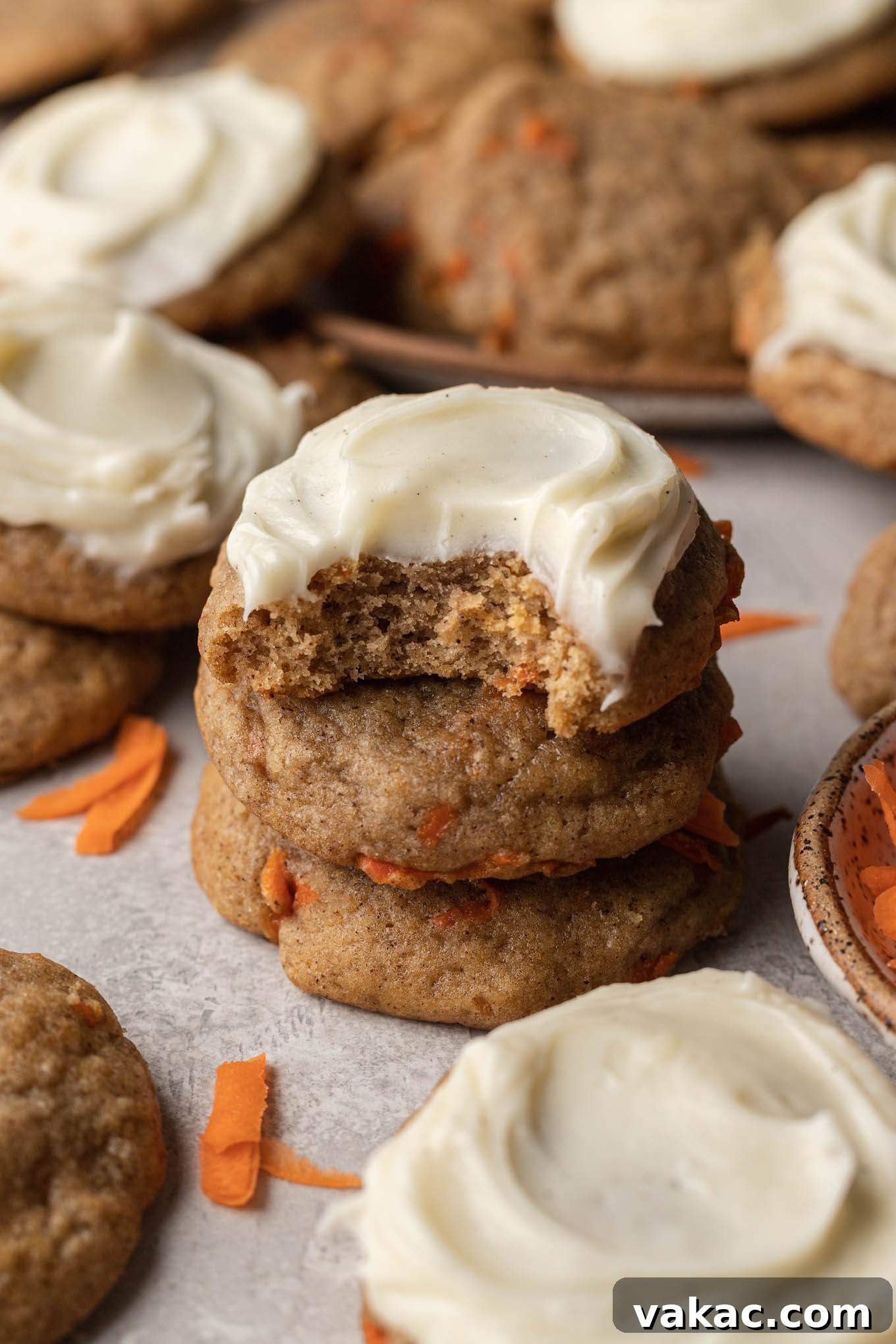 A stack of frosted carrot cake cookies, amongst other cookies. 
