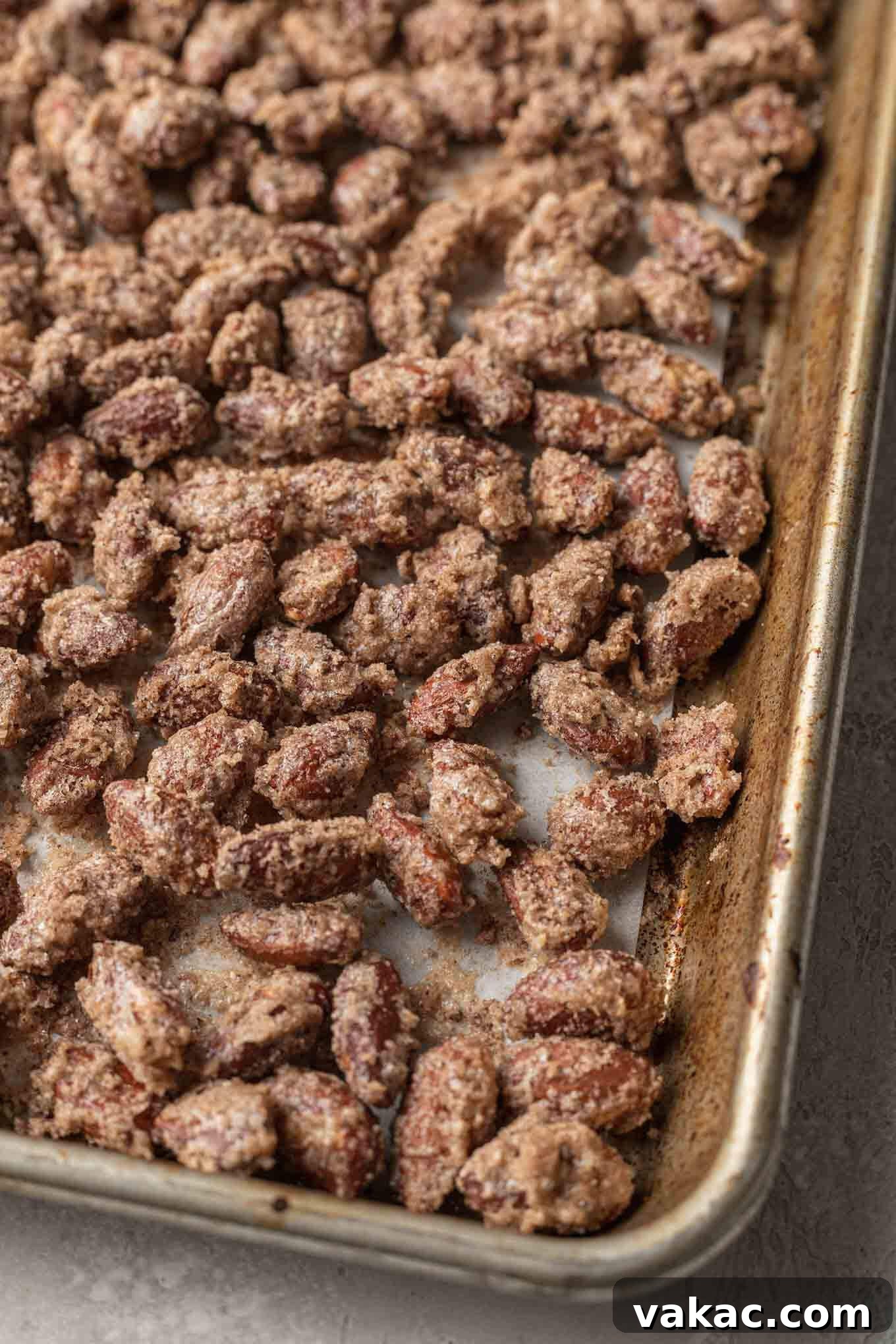 Sugar-Kissed Almonds 7 Cinnamon candied almonds on a parchment paper-lined baking sheet.