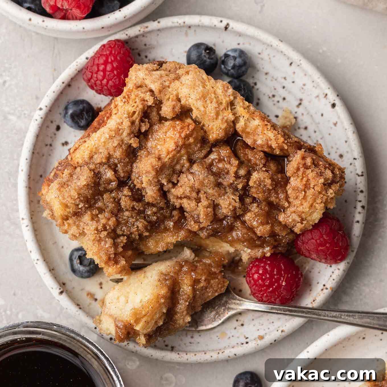 Overnight French Toast Bake 11 An overhead view of a delectable slice of French toast casserole on a white plate, showcasing its golden crust, soft interior, and inviting crumb topping.