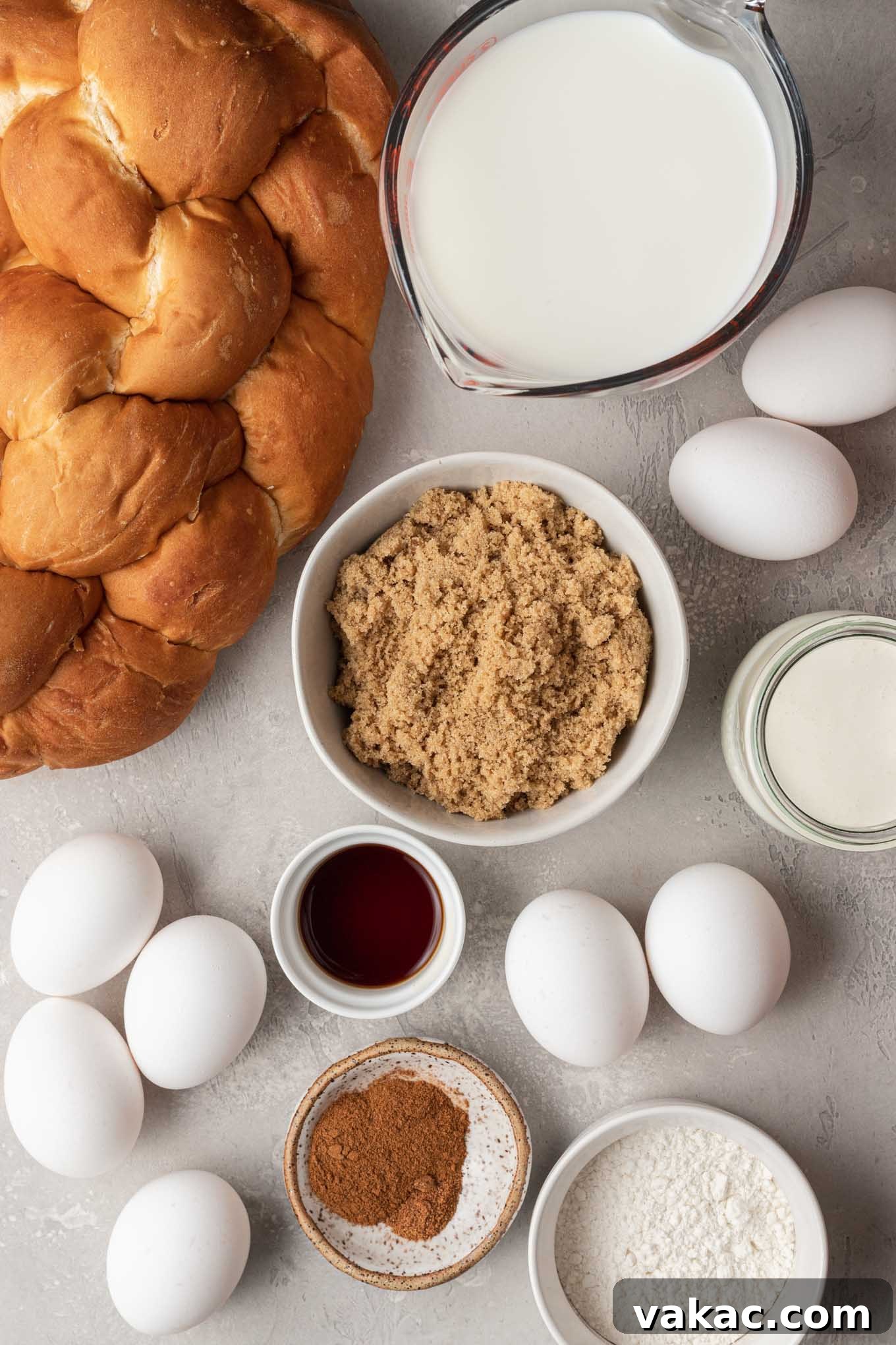 Overnight French Toast Bake 3 An overhead view showcasing the array of fresh ingredients laid out for making overnight baked French toast casserole, including a loaf of challah bread, eggs, milk, cream, butter, and spices.