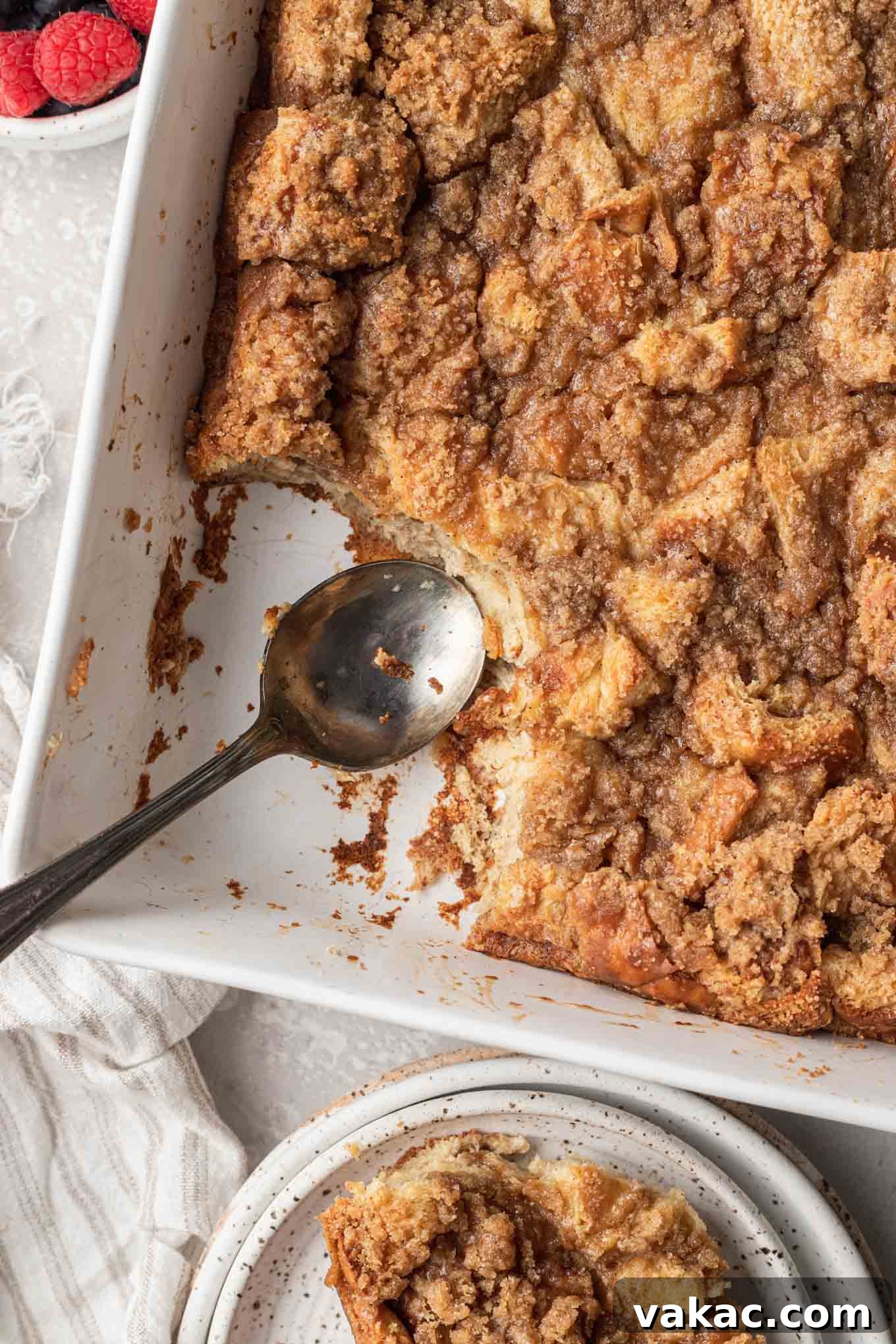 Overnight French Toast Bake 10 An overhead view of a white rectangular casserole dish filled with baked French toast, with one serving missing, revealing the soft, custardy interior and golden crust.
