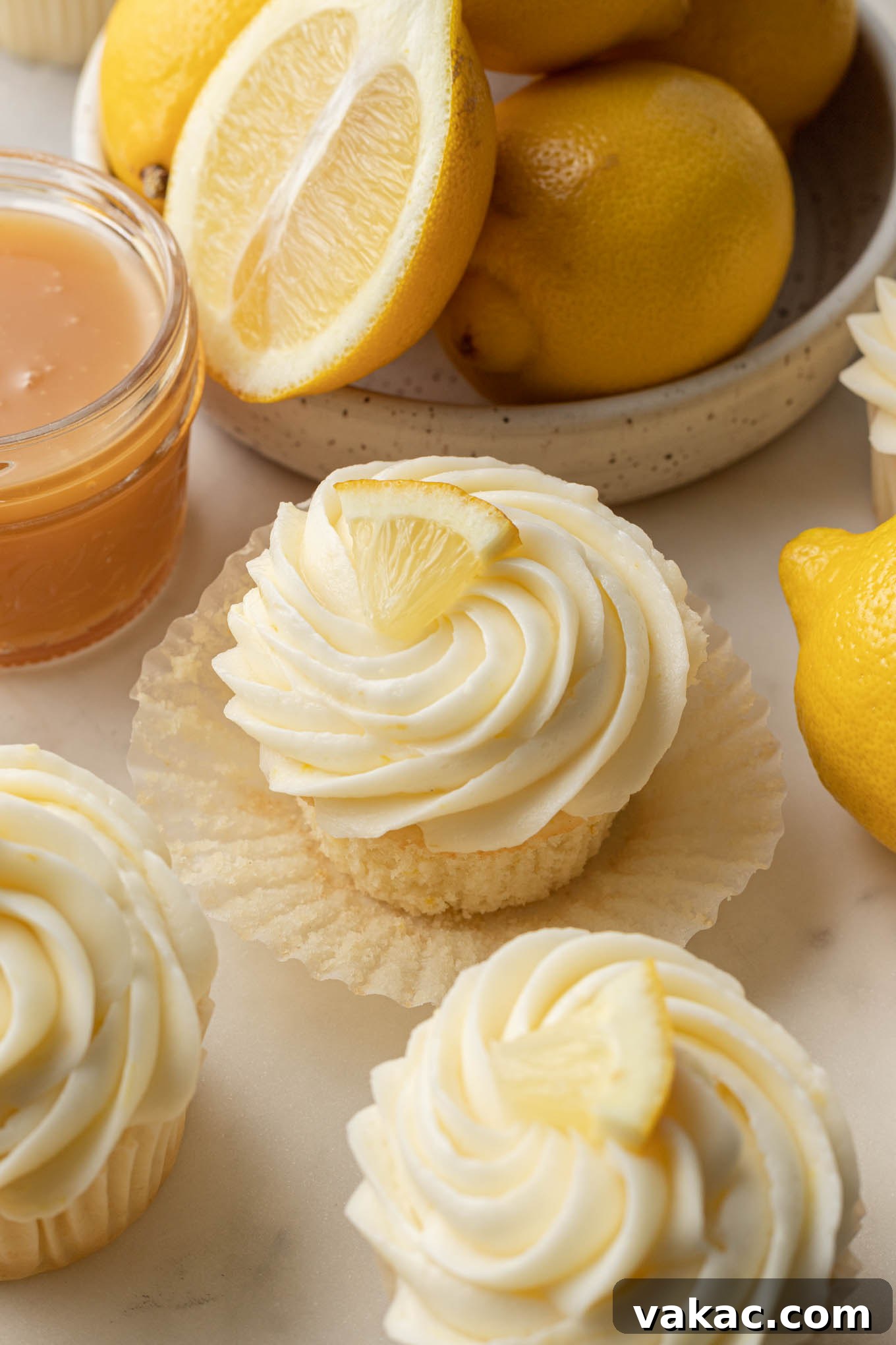 Sunshine Lemon Bliss Cupcakes 2 Beautifully decorated lemon cupcakes in pastel liners, surrounded by vibrant fresh lemons, ready to be served.