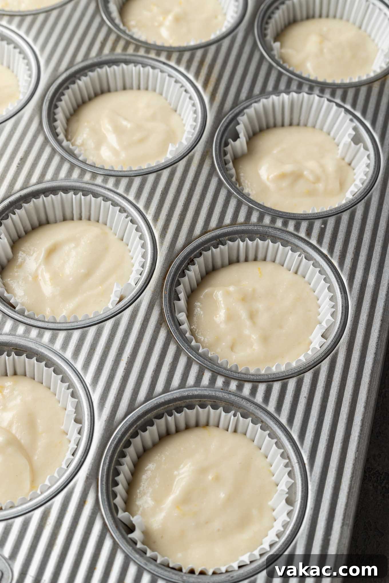 Sunshine Lemon Bliss Cupcakes 7 Muffin tins lined with white cupcake papers, each filled with an even portion of lemon cupcake batter, waiting to be baked.