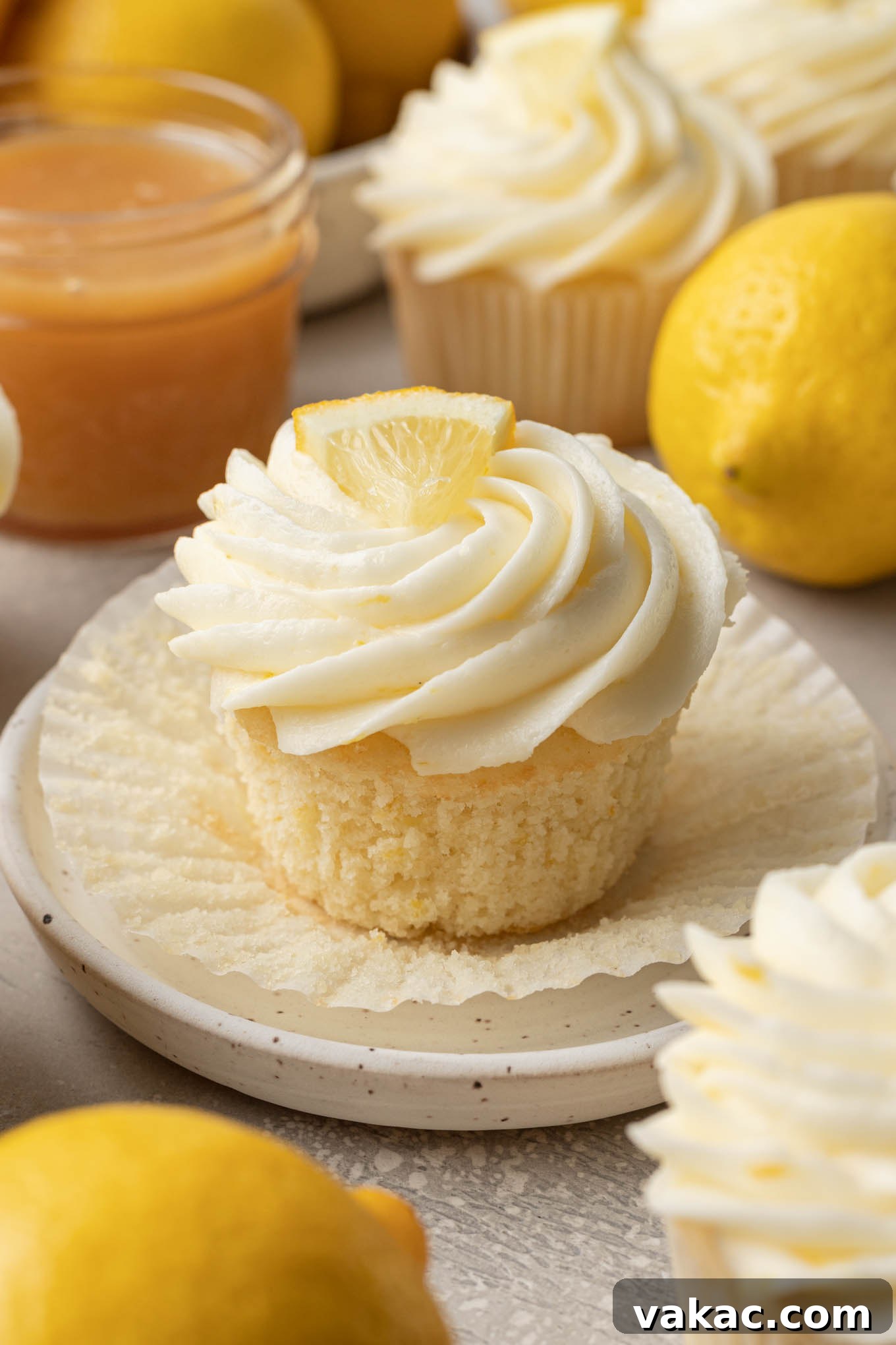 Sunshine Lemon Bliss Cupcakes 8 A close-up view of a perfectly baked lemon cupcake, its liner peeled back to reveal a generous filling of bright yellow lemon curd within its moist crumb.
