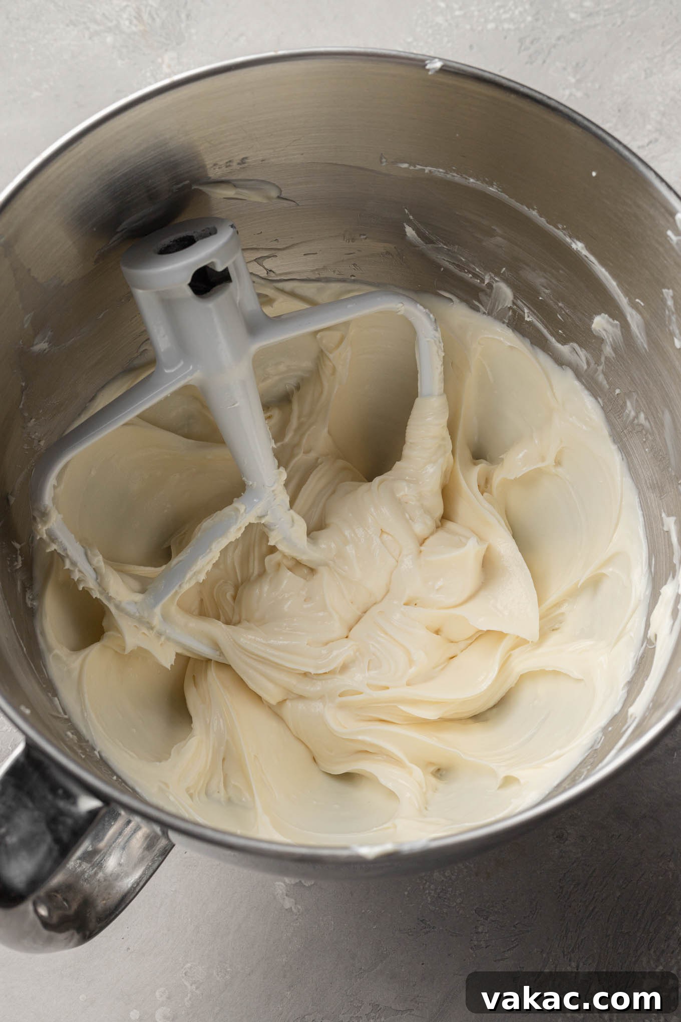 Effortless Mini Cheesecake Delights 5 An overhead view of the creamy no-bake cheesecake filling being prepared in a mixing bowl, attached to a stand mixer with a paddle attachment.