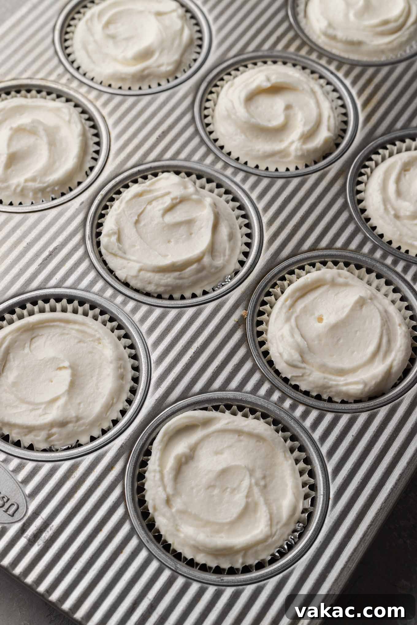 Effortless Mini Cheesecake Delights 7 An overhead view of a muffin pan with cups generously filled with the smooth cheesecake filling.