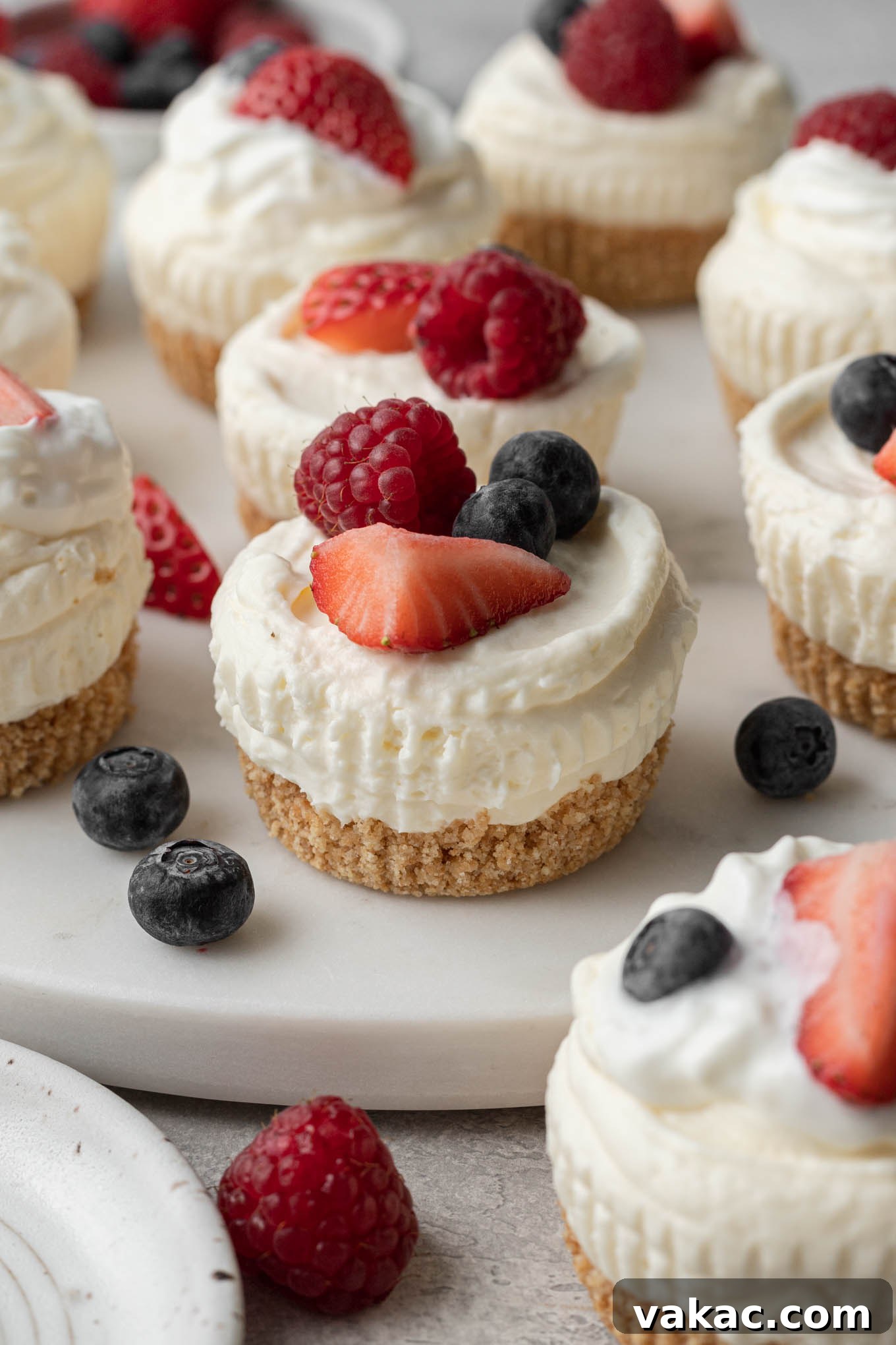 Effortless Mini Cheesecake Delights 8 A stunning platter of mini no-bake cheesecakes, each generously topped with an assortment of fresh berries, ready for serving.