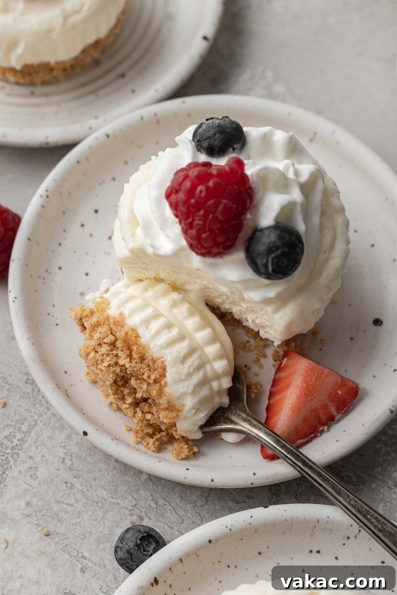 Effortless Mini Cheesecake Delights 9 An inviting overhead view of an individual no-bake cheesecake topped with a generous dollop of whipped cream and fresh berries, with a fork taking a perfect bite.