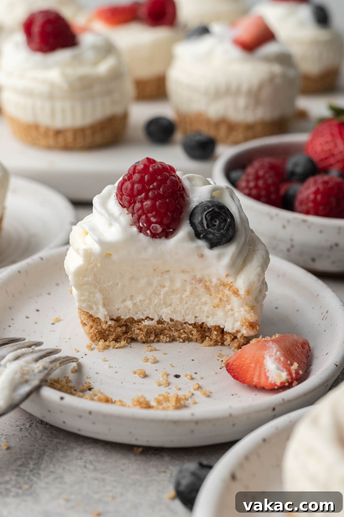 Effortless Mini Cheesecake Delights 10 A close-up side profile of a no-bake mini cheesecake, revealing its distinct crust and creamy filling layers, with a bite missing to show its delightful texture.