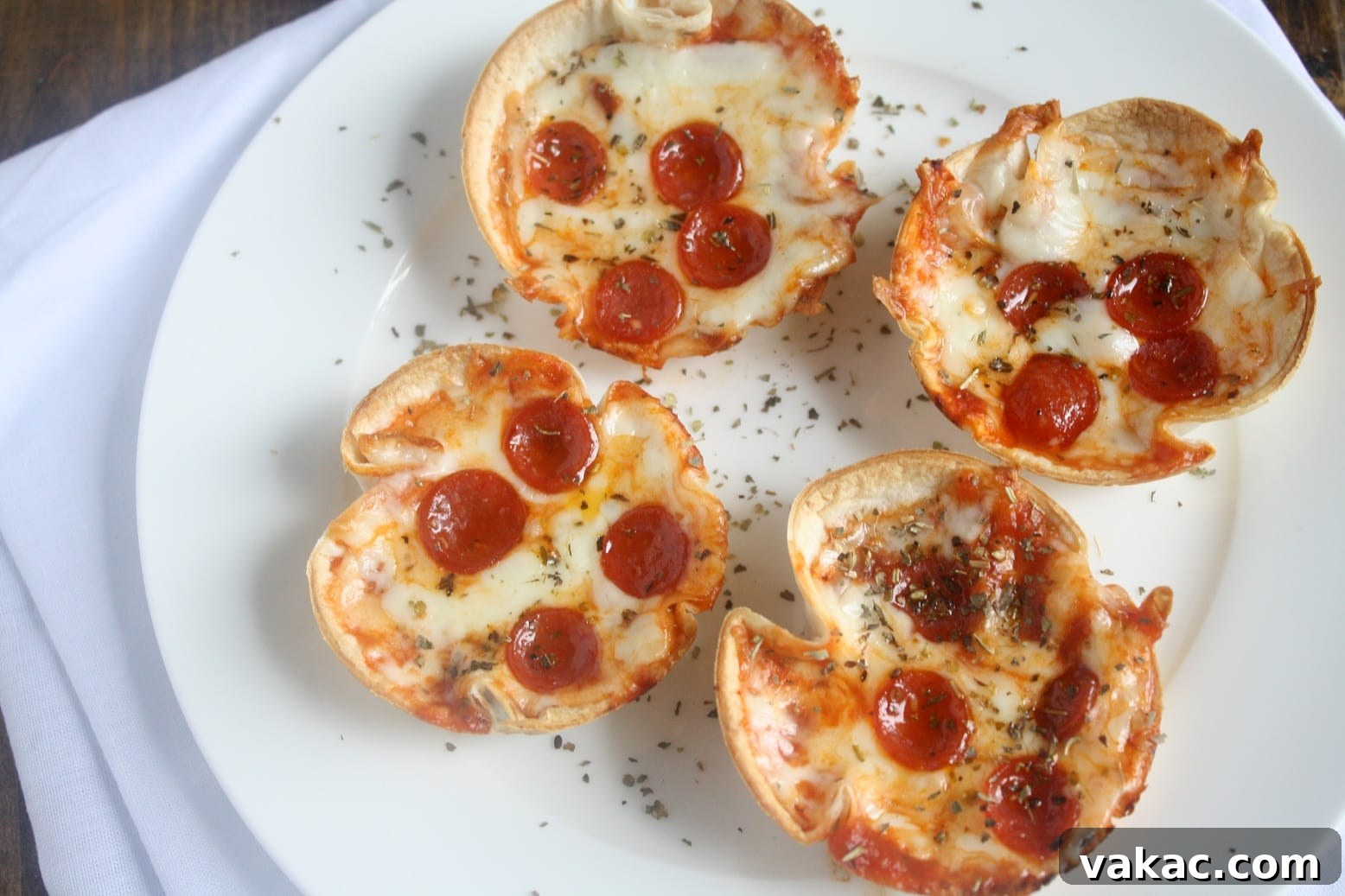 Crispy Tortilla Pizzettes 3 Close-up shot of individual mini tortilla pizzas with melted cheese and pepperoni, baked in a muffin tin.