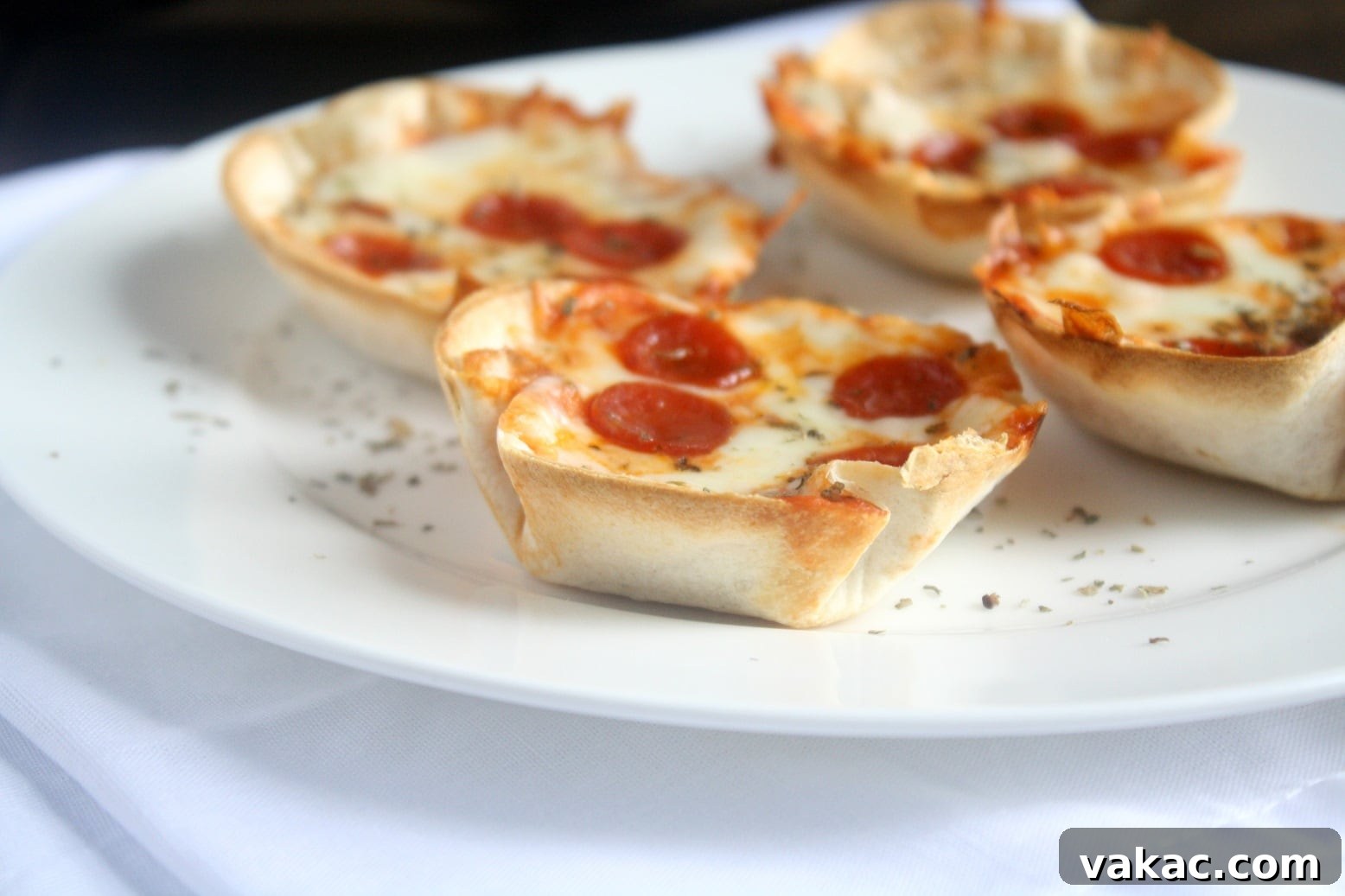 Crispy Tortilla Pizzettes 4 Freshly baked mini tortilla crust pizzas presented in a muffin pan, showcasing their golden-brown edges.