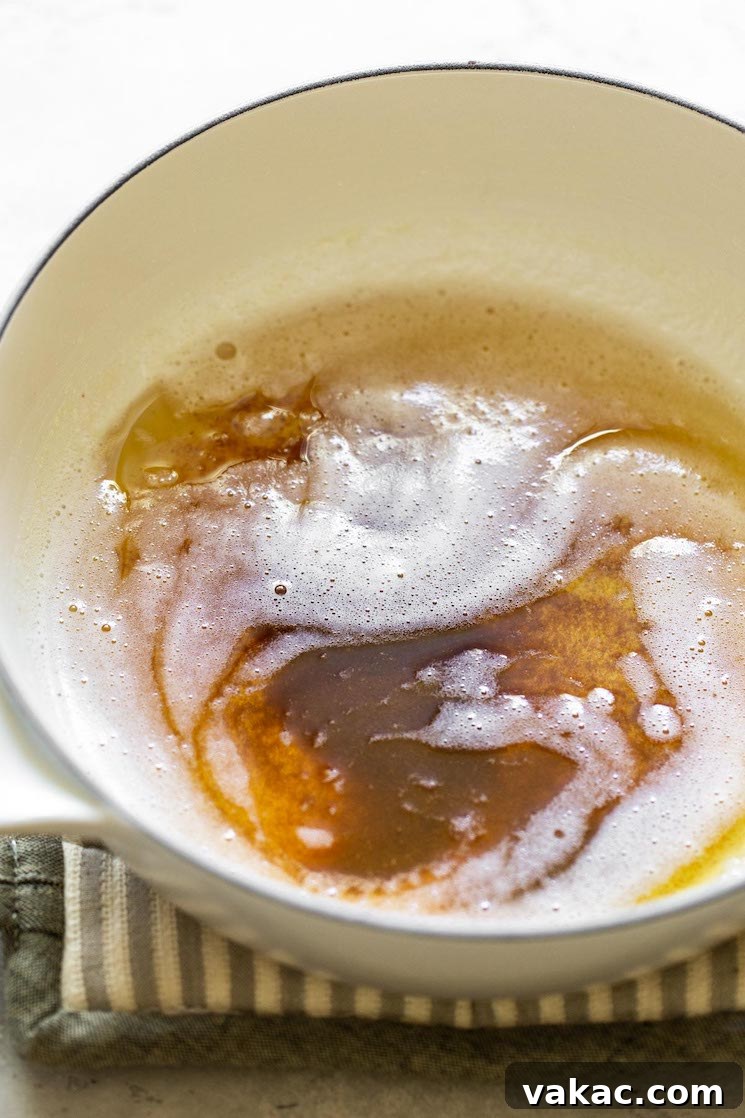 Butter melting and beginning to brown in a light-colored saucepan over medium heat, releasing a rich, nutty aroma.