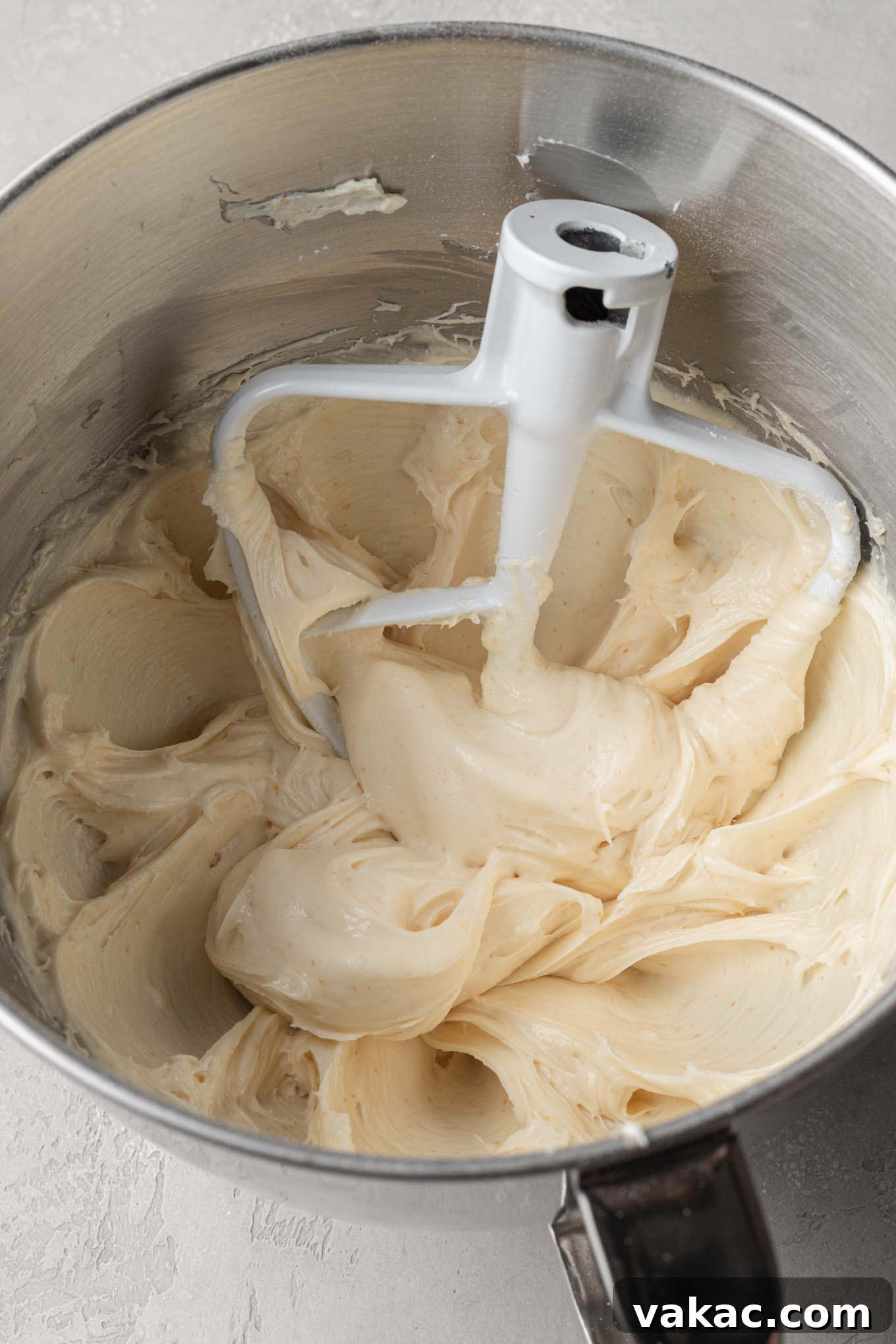 Creamy brown butter cream cheese frosting swirling in the bowl of a stand mixer, perfectly smooth and ready for cake.