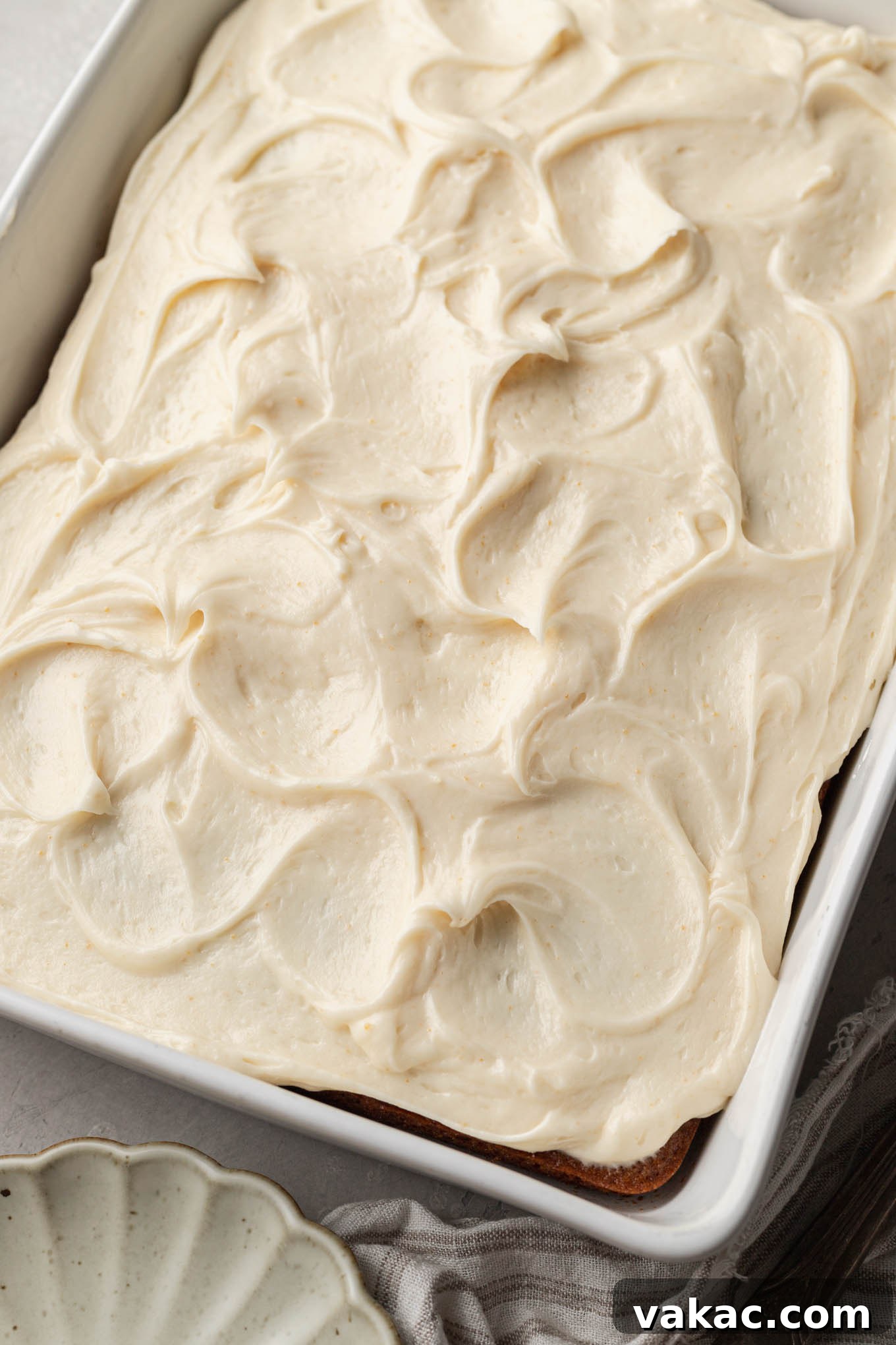 An inviting overhead shot of a freshly frosted applesauce cake in a rectangular pan, adorned with luscious brown butter cream cheese frosting, ready to be served.