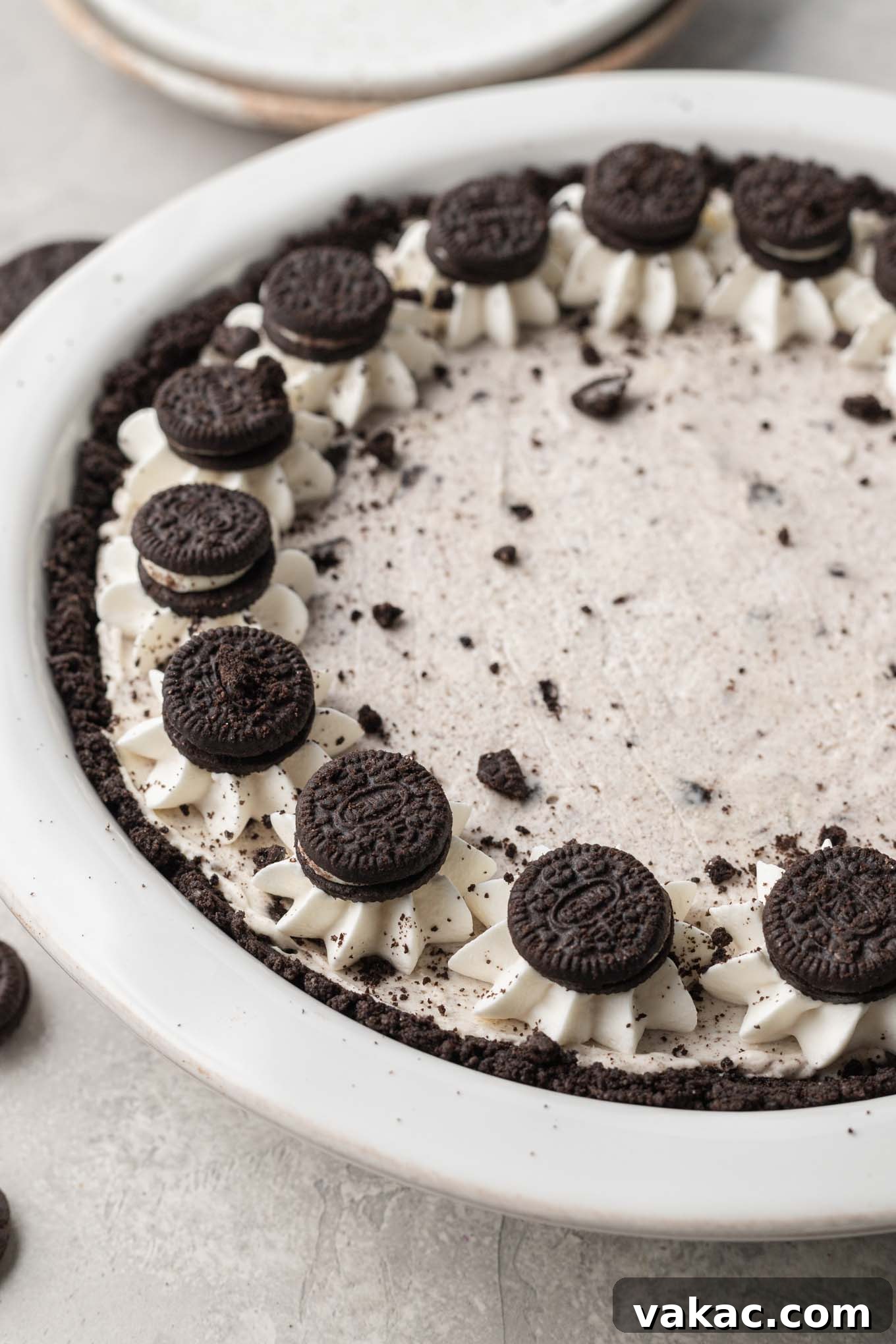 Irresistible Oreo Dream Pie 2 A side view of an Oreo pie with whipped cream piped around the edges and mini Oreos pressed on top of the whipped cream.